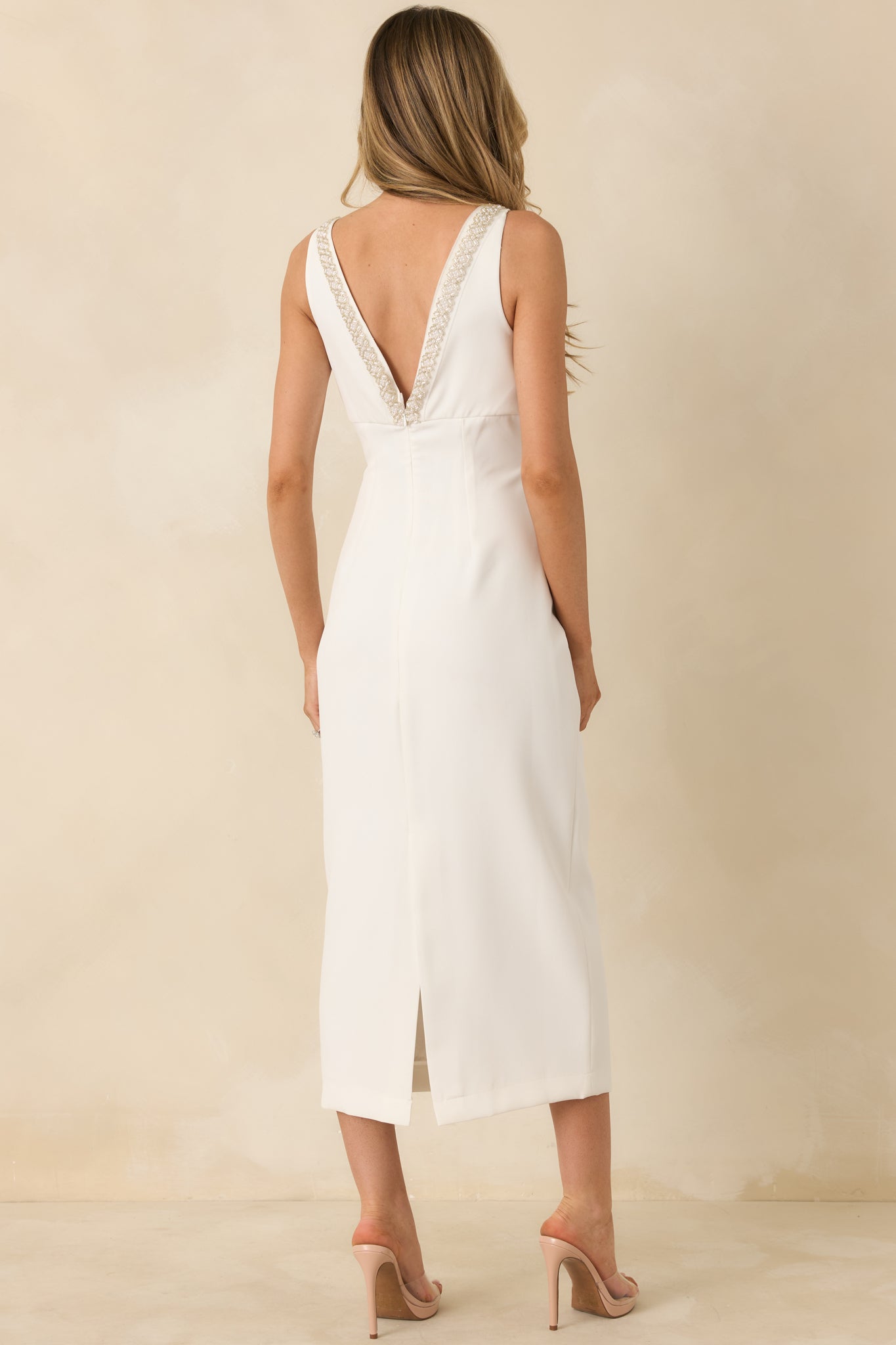 Rear view of white midi dress showing tonal beading along the back, fitted bodice, and back slit for ease of movement.