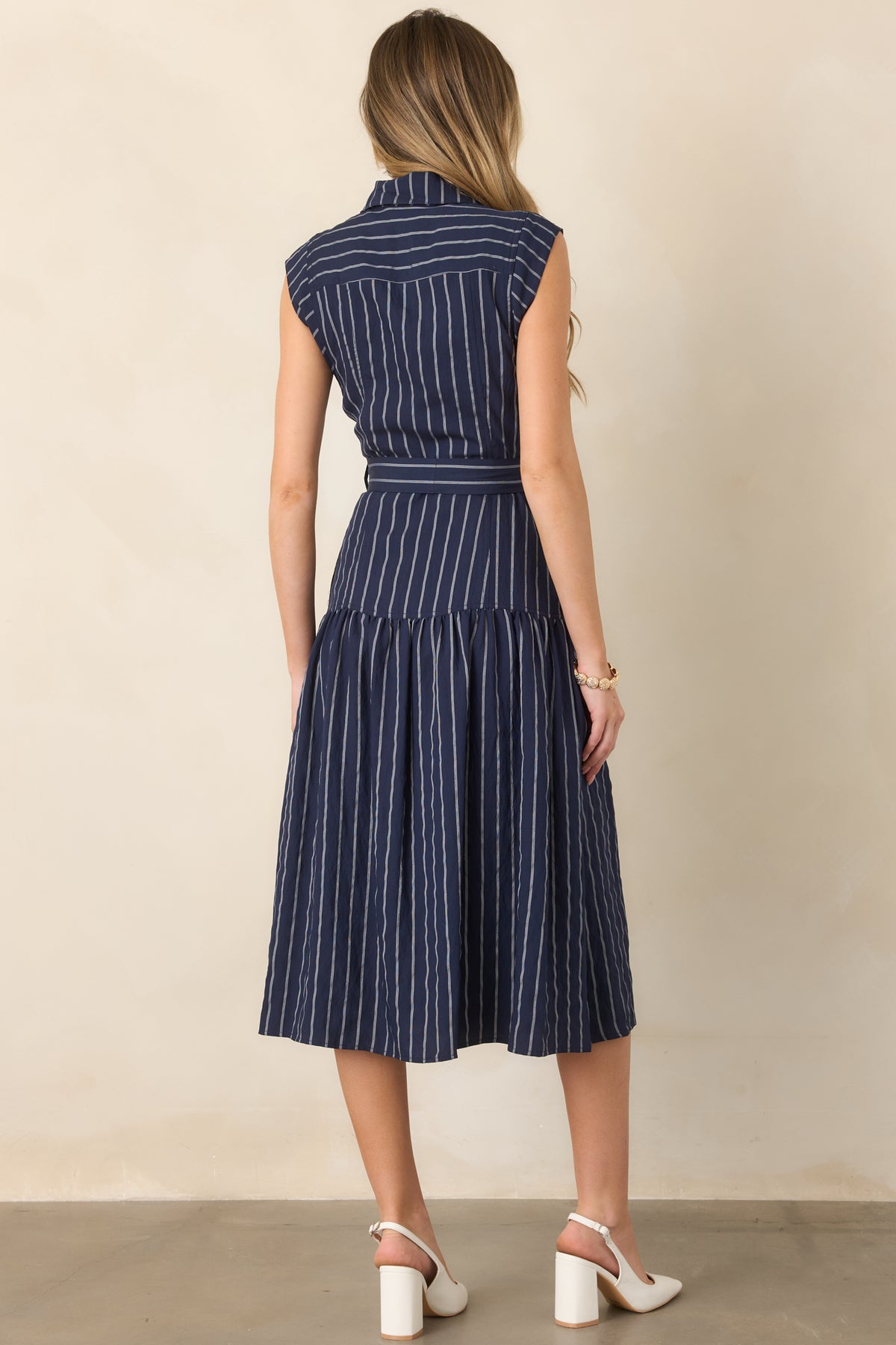 Rear view of the sleeveless striped midi dress showcasing the self-tie waist, drop-waist seam, and full skirt.