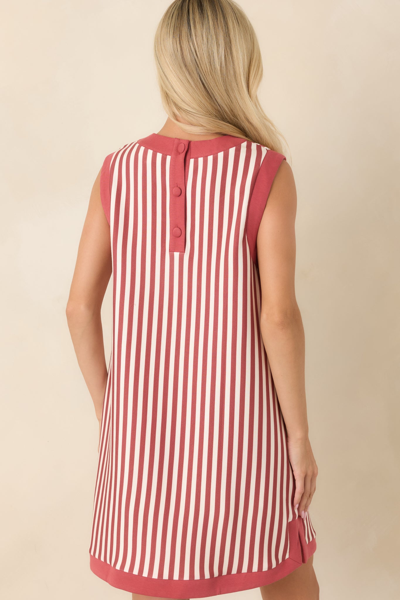 Rear view of the striped mini dress showcasing the covered buttons at the back neckline, sleeveless silhouette, and vertical stripe pattern.