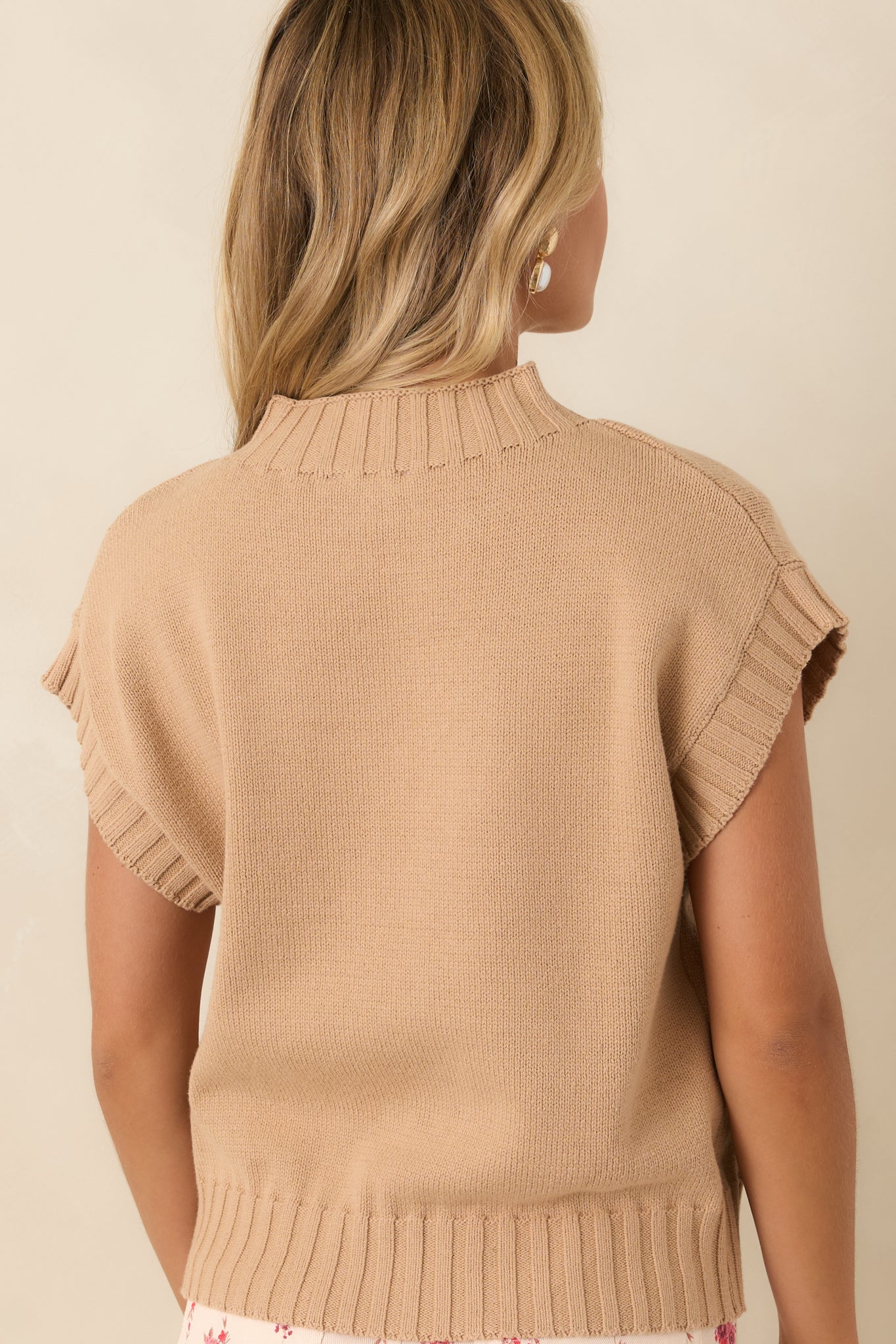 Rear view of the tan knit sweater featuring a relaxed boxy silhouette, short sleeves, ribbed hem, and soft textured knit.