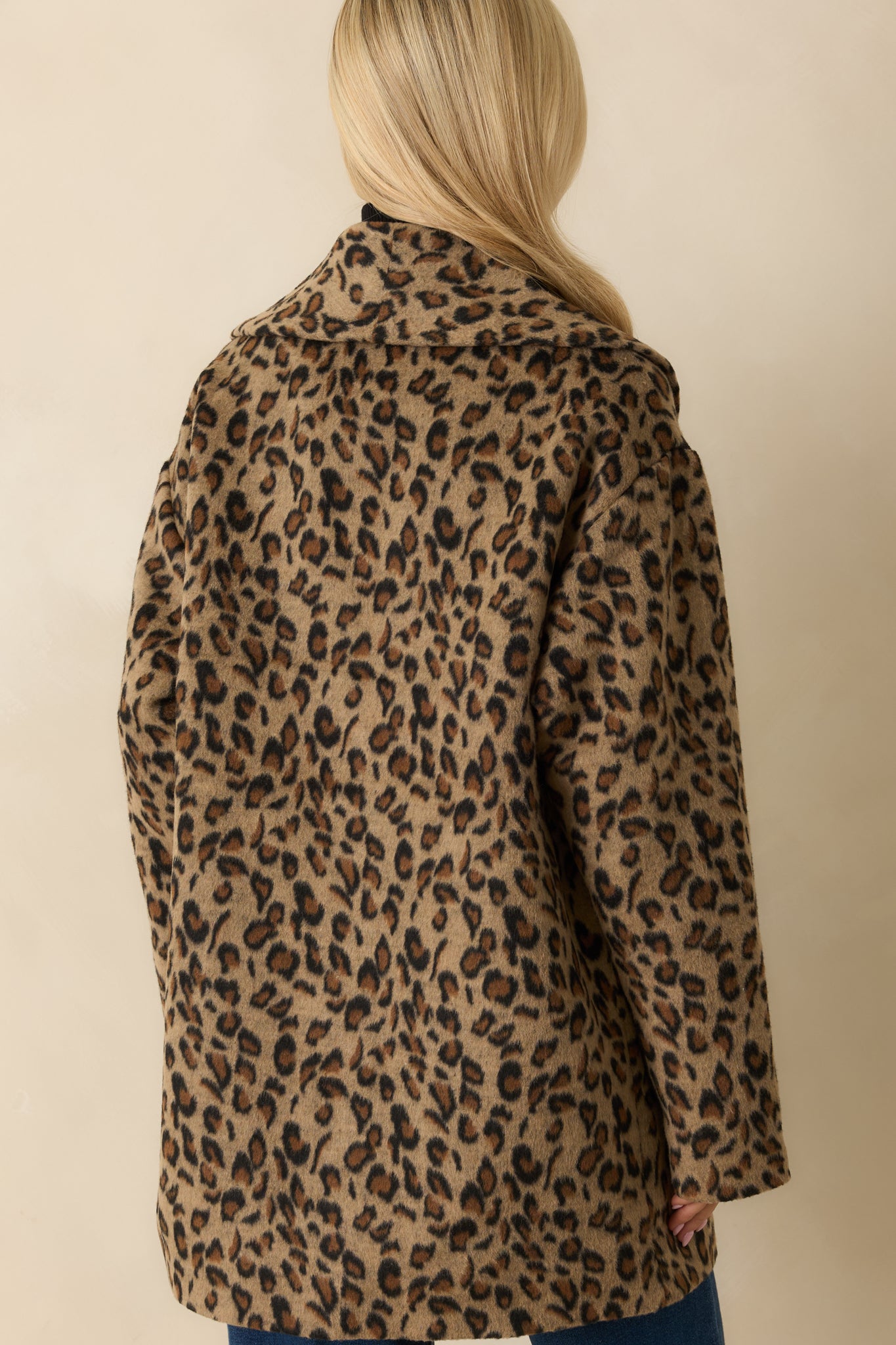 Rear view of tan longline coat showing full lining, relaxed fit, and long sleeves.