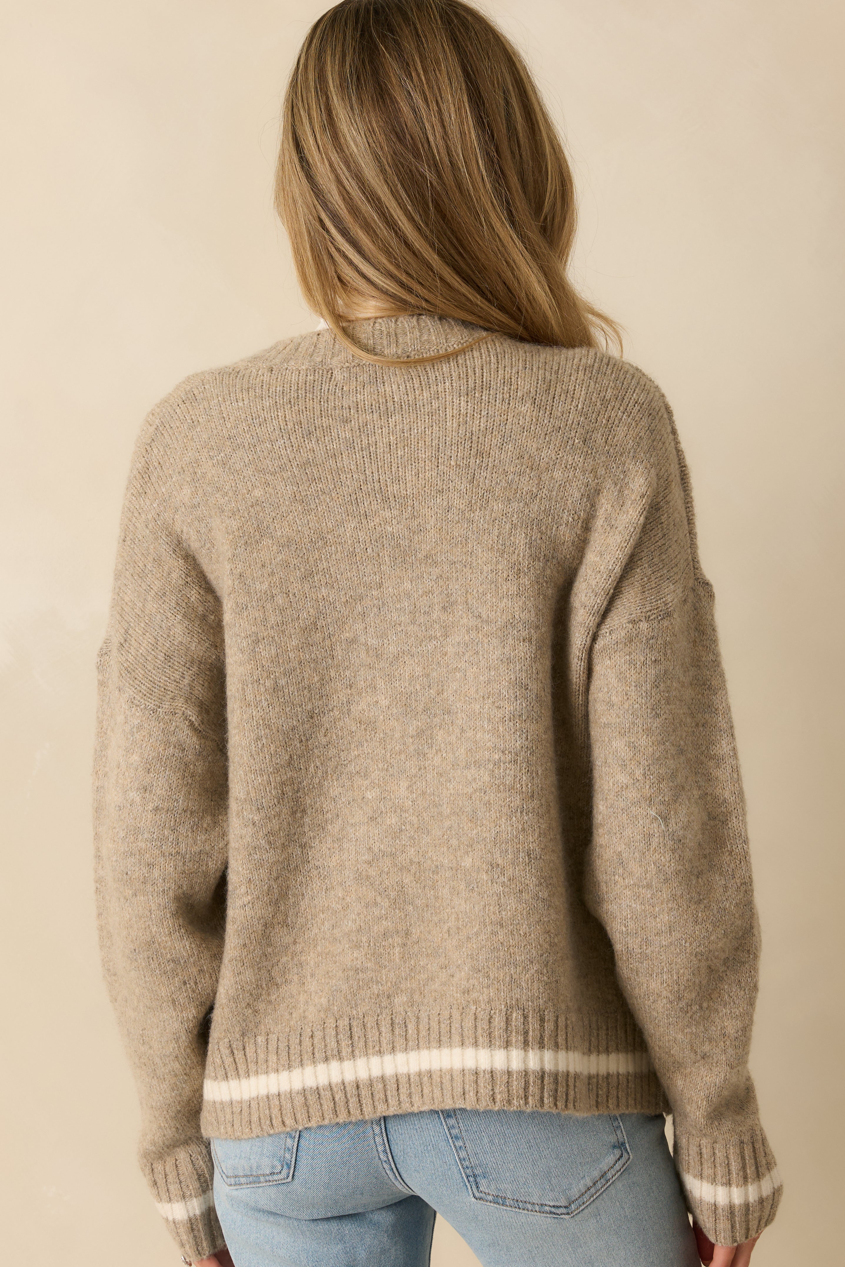 Rear view of taupe knit pullover showing long sleeves, ribbed trim, and relaxed fit without chest lettering.