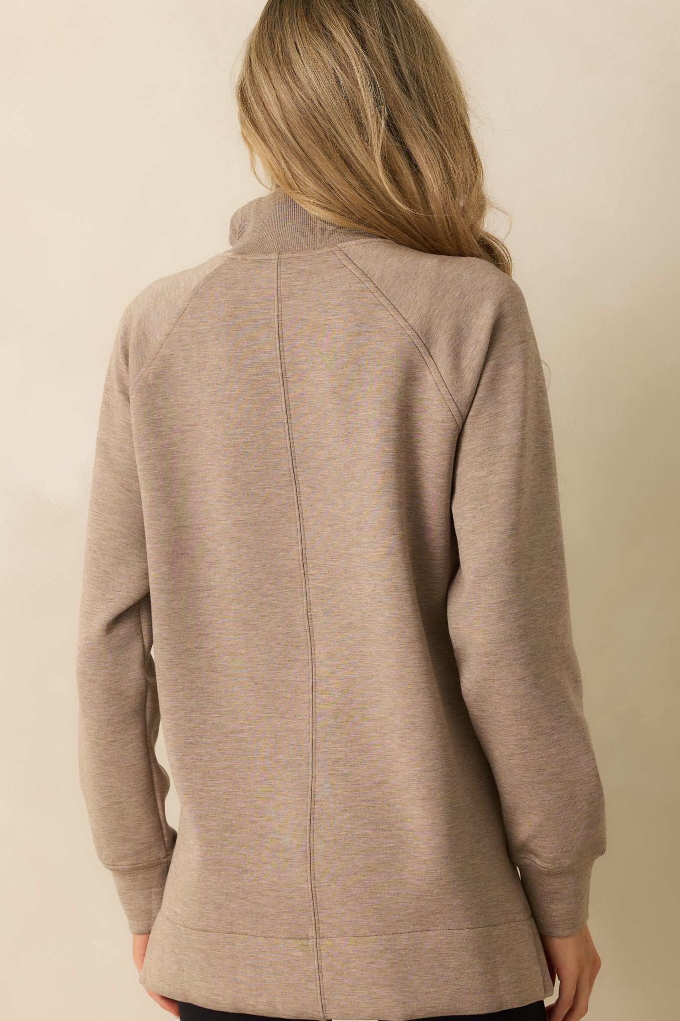 Rear view of the taupe pullover with a tunic-length drape and relaxed fit.