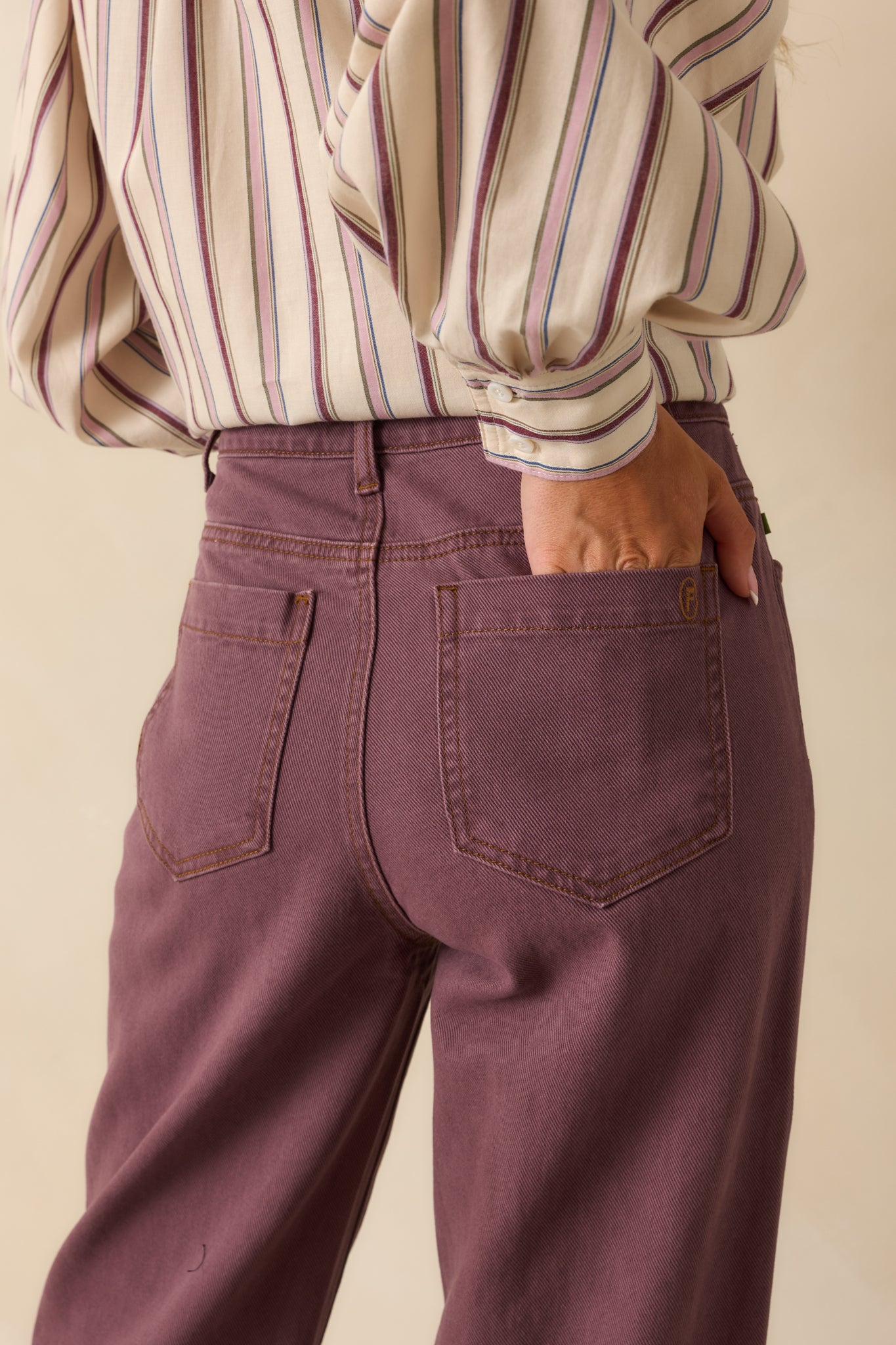 Rear view of the violet jeans showing functional back pockets, structured silhouette, and straight-leg shape.