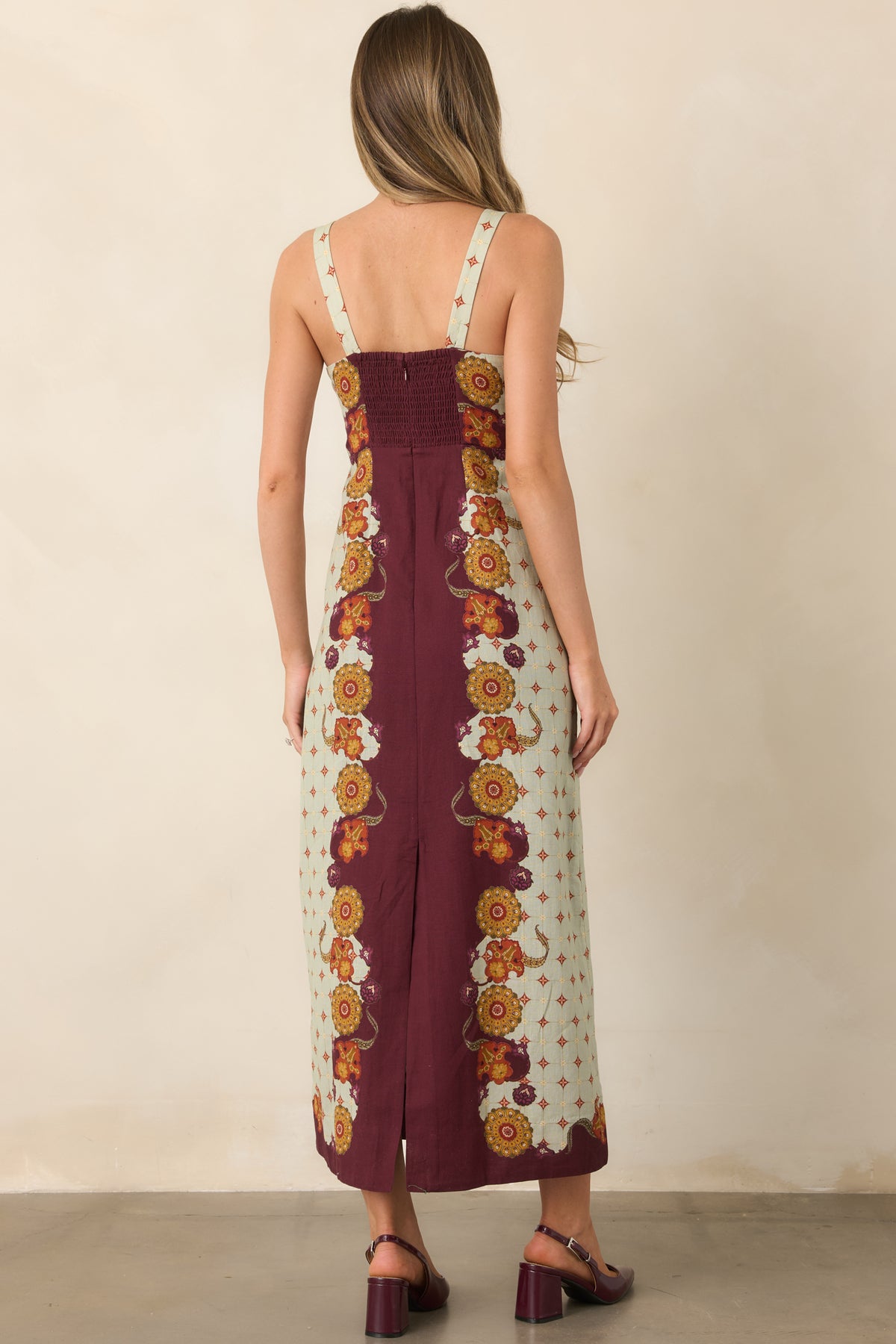 Rear of the wine midi dress showing the smocked panel, concealed zipper, and hem slit.