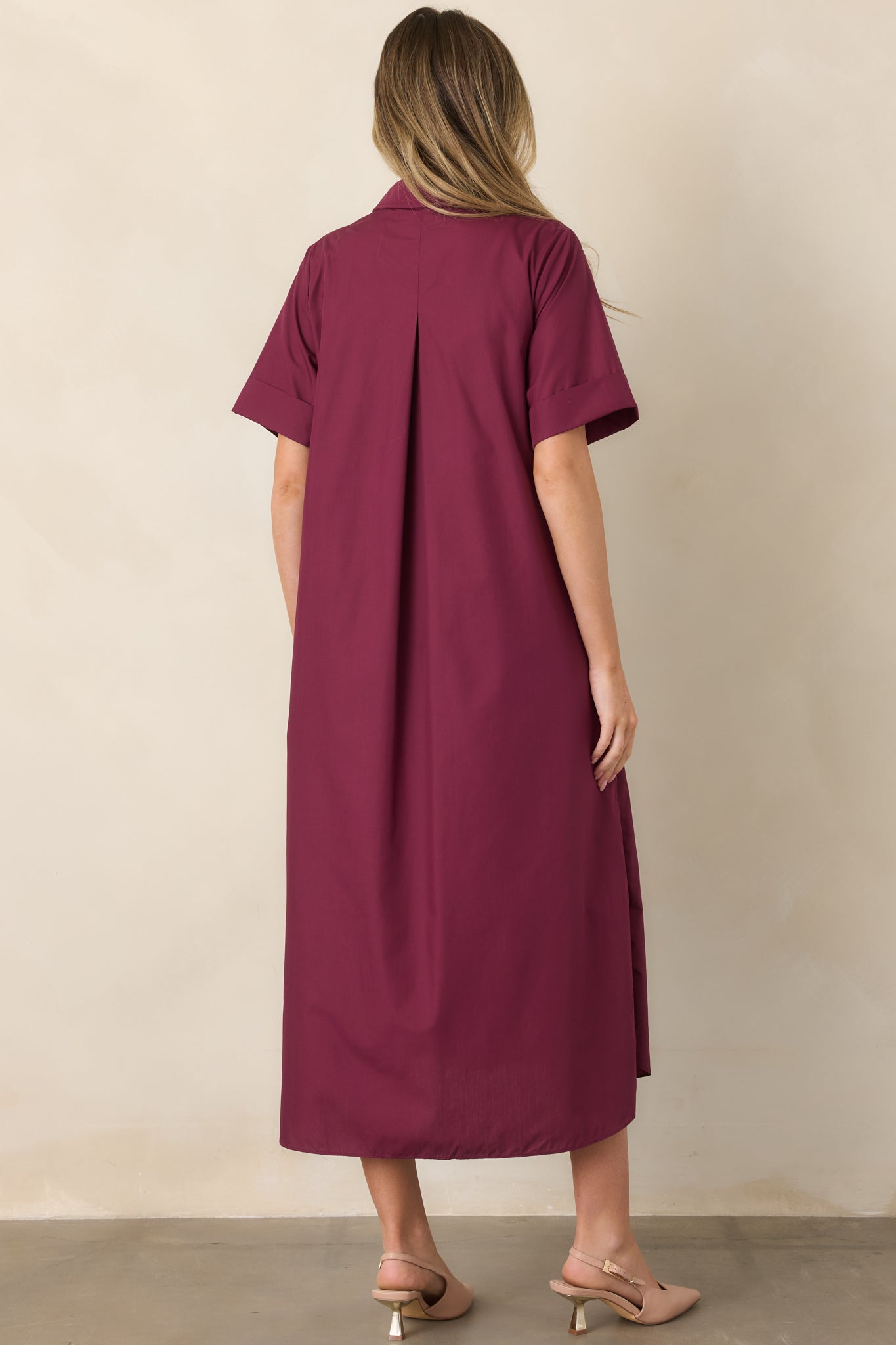 Rear view of the wine red woven maxi dress showcasing its relaxed A-line silhouette, rolled short sleeves, flowing length, and side slits.