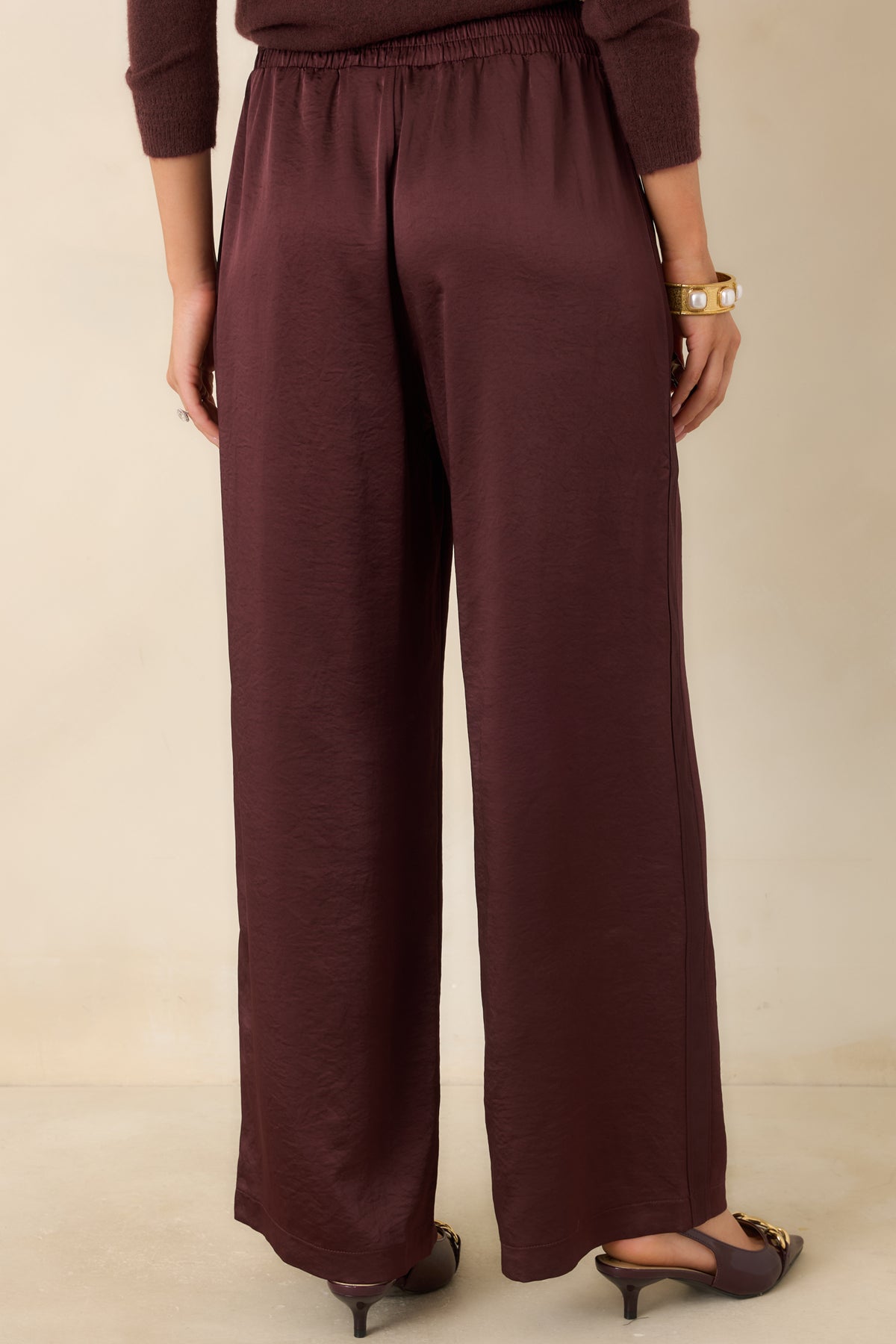Rear of the wine wide-leg pants showing the elasticized back waistband and flowing plum-toned fabric.