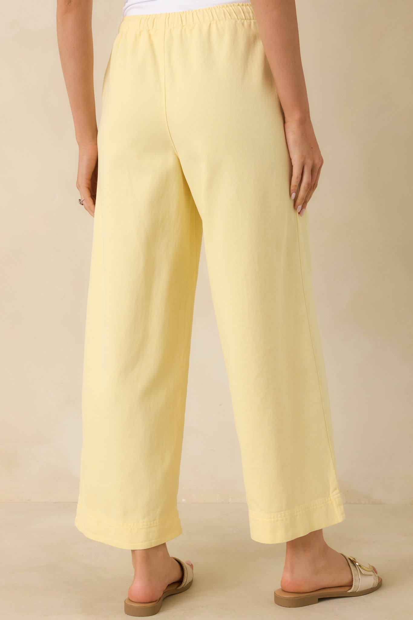 Rear view of the yellow wide-leg pants showing the elastic waistband, relaxed drapey fit, and smooth fabric flow.