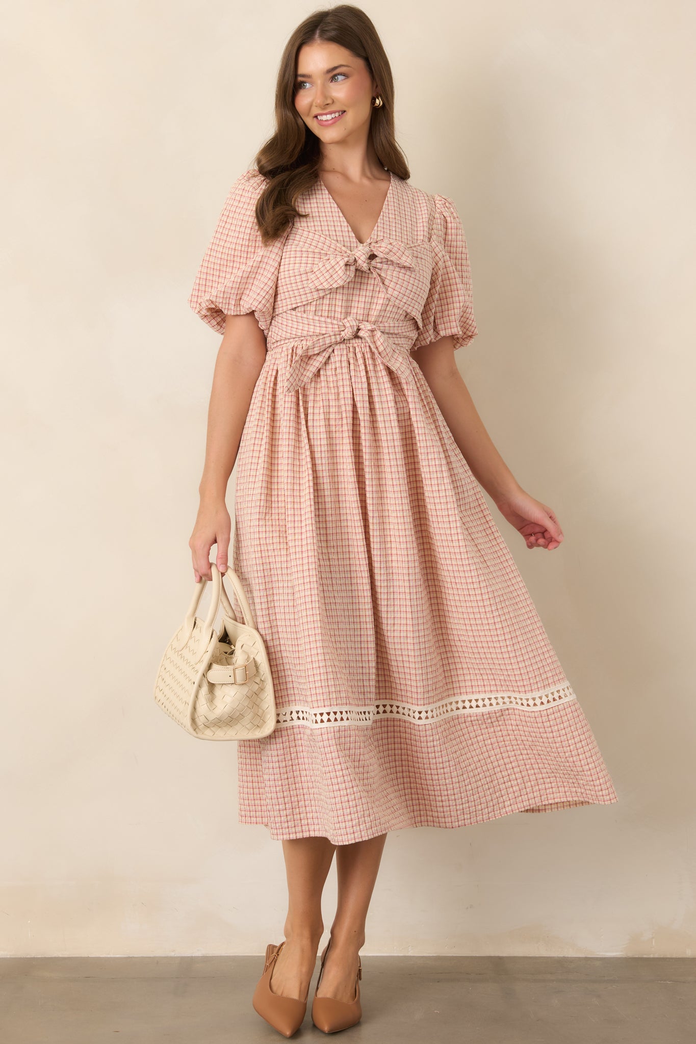 Feminine red and beige plaid dress showcasing oversized double tie details, puff sleeves, an elasticized waist, and graceful full skirt.
