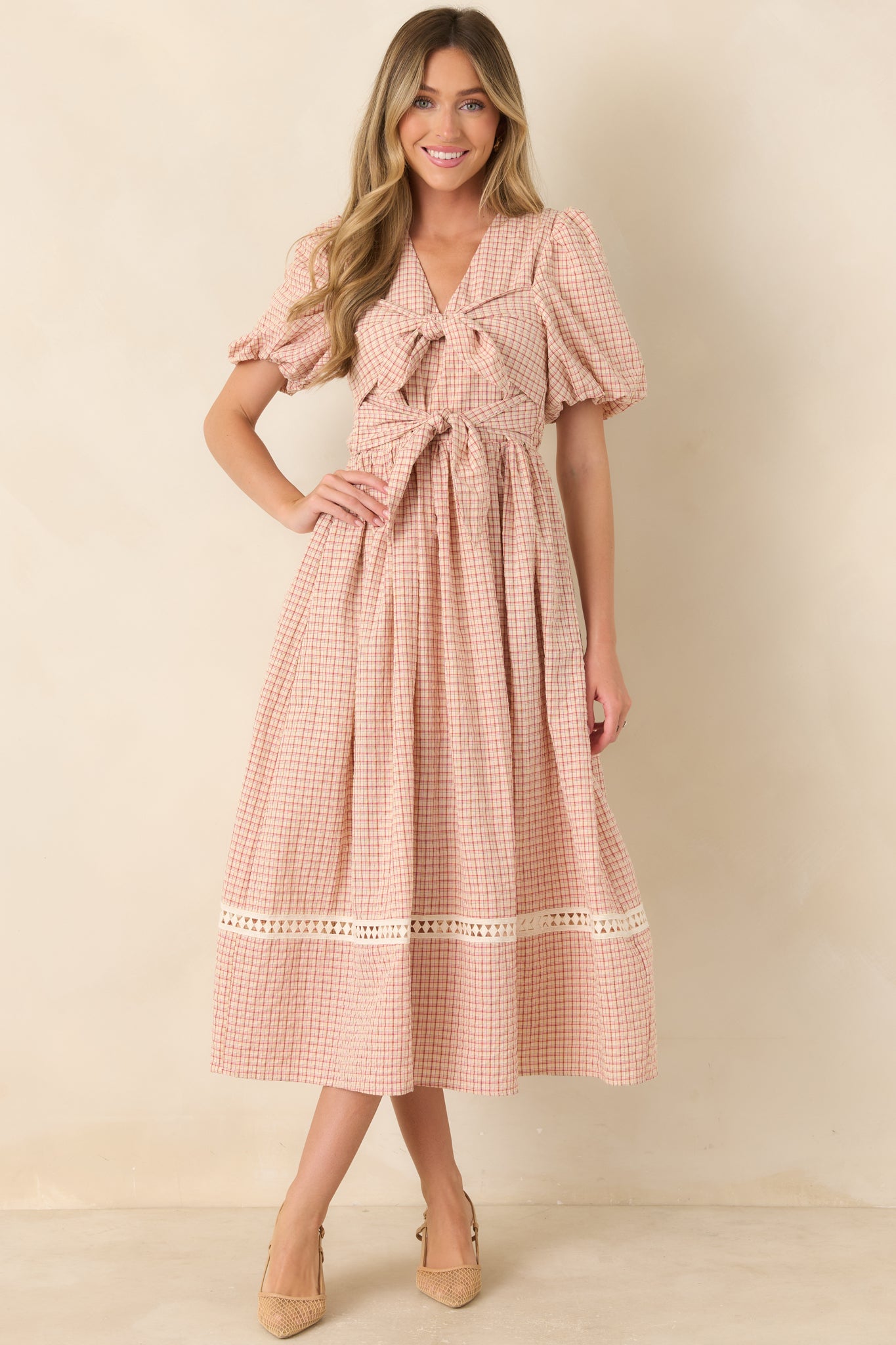 Red and beige cotton-blend dress featuring a fitted bodice, statement double ties, elastic waist, puffed sleeves, and a feminine full midi skirt.