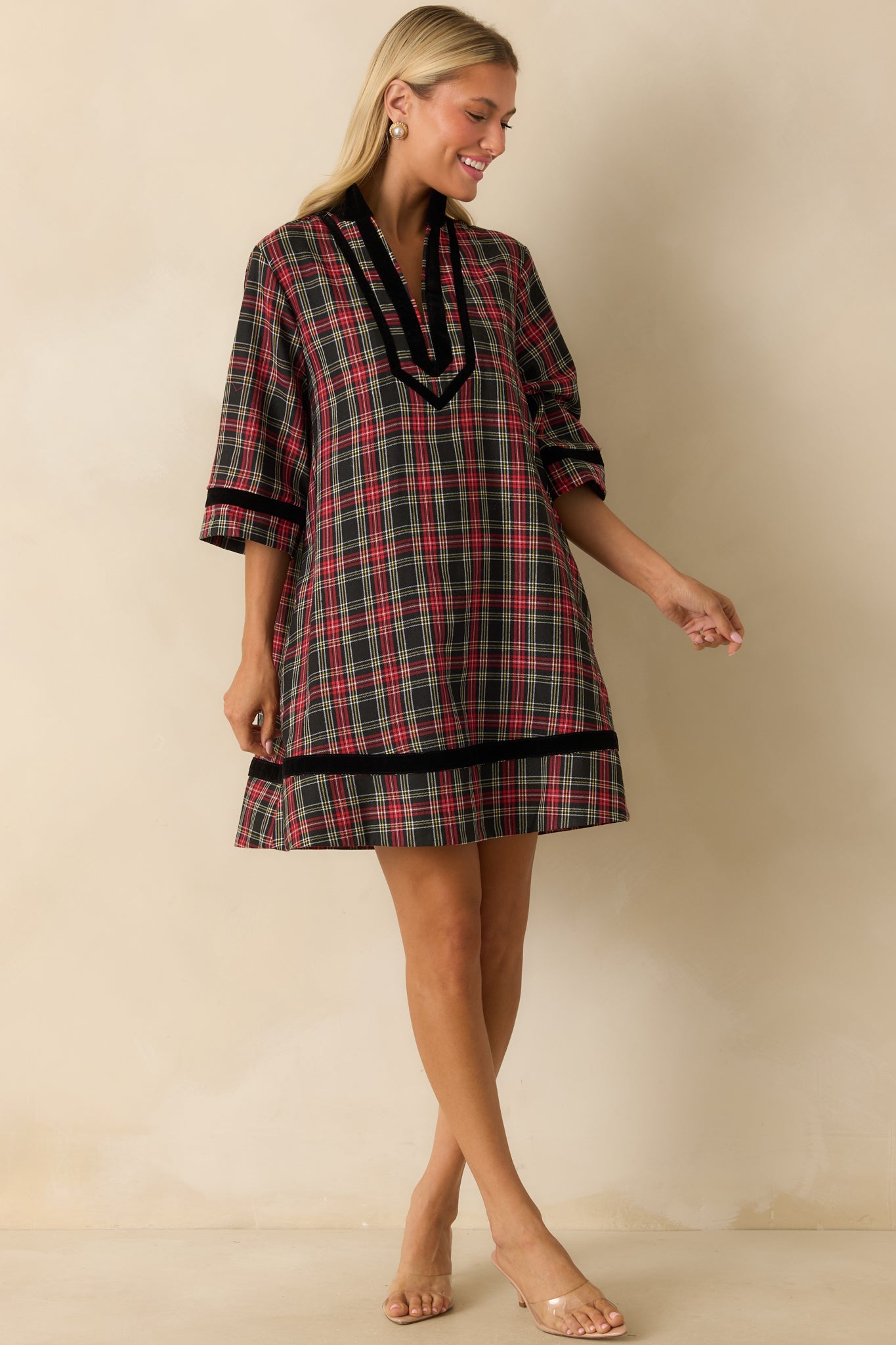 Relaxed-fit red and black plaid mini dress highlighting elbow-length sleeves, split neckline, and subtle side pockets.