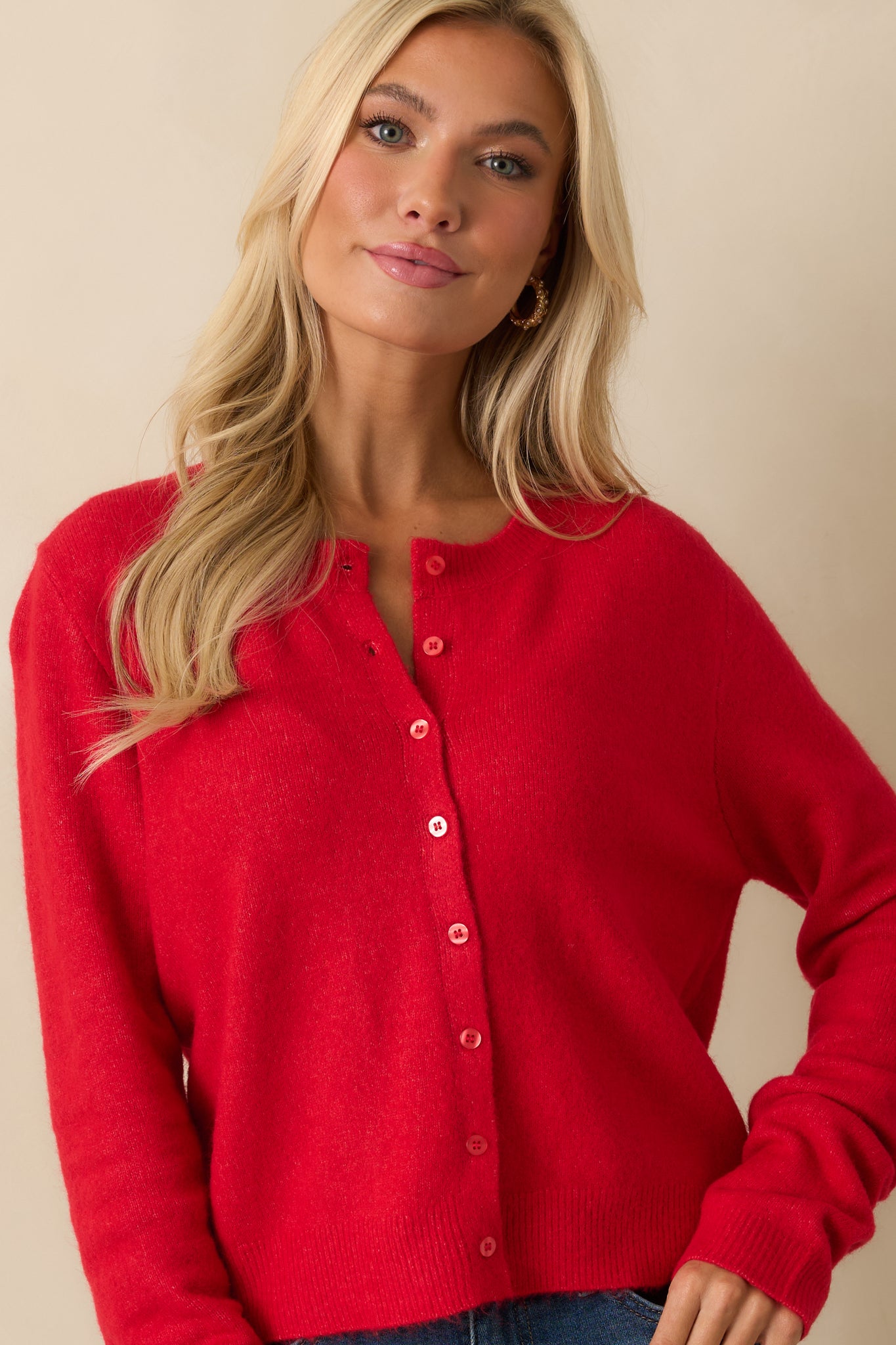 Detail view of front of red button-up cardigan, emphasizing relaxed fit and soft knit material.