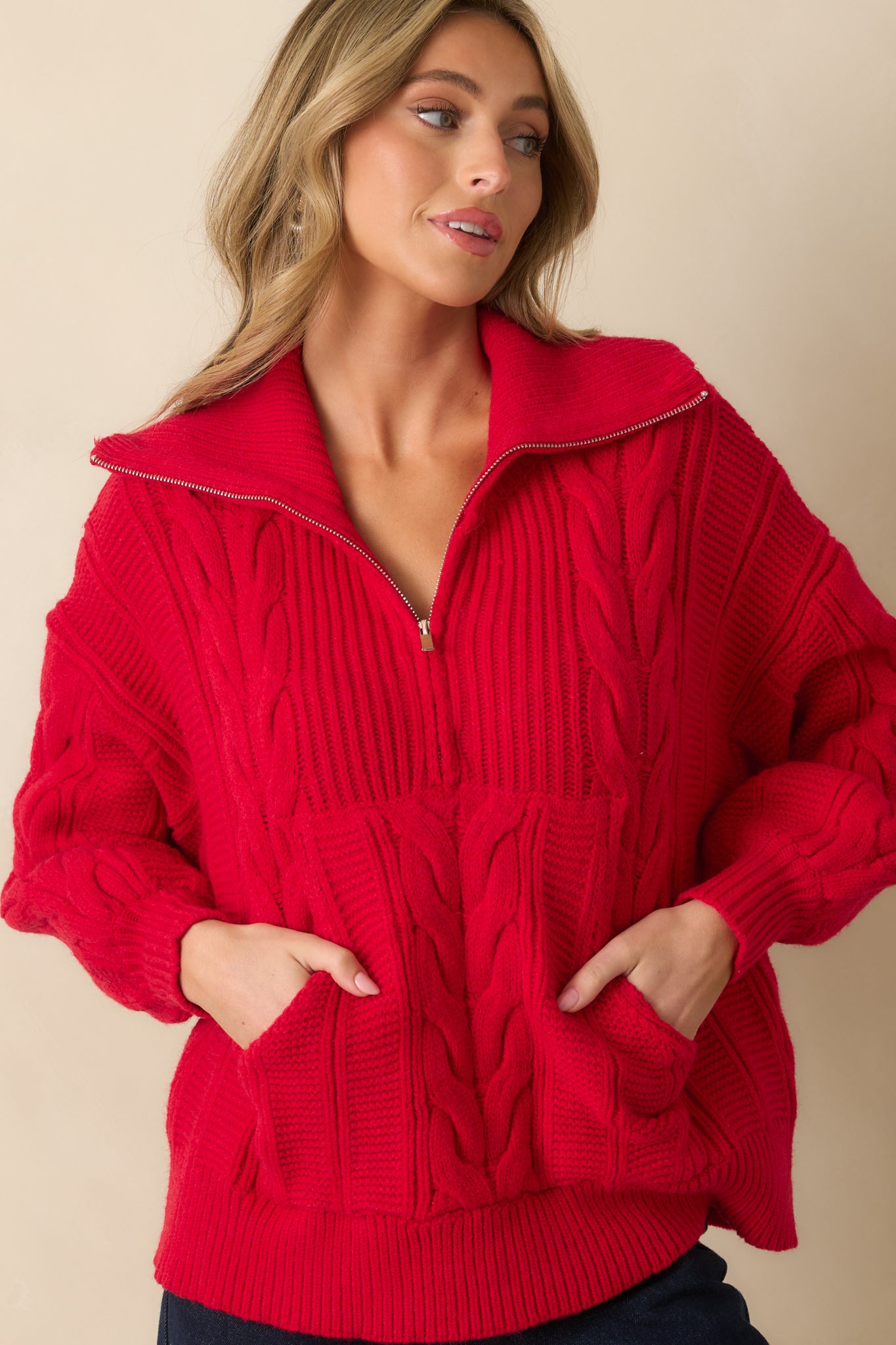 Red cable knit sweater emphasizing the drop shoulder design and ribbed edges.