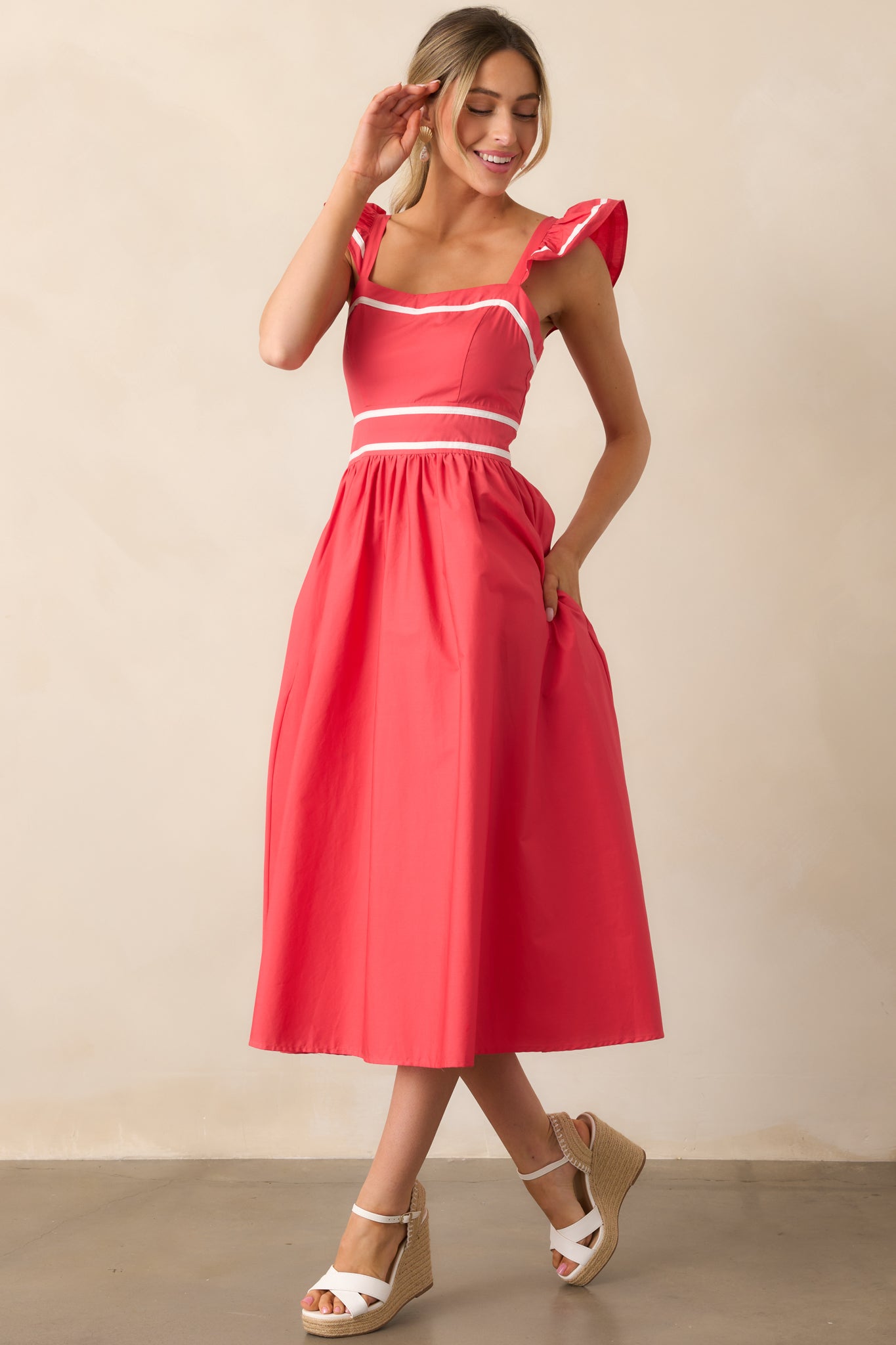 A modern red dress featuring a relaxed yet structured shape, white hem accents, and practical side pockets.