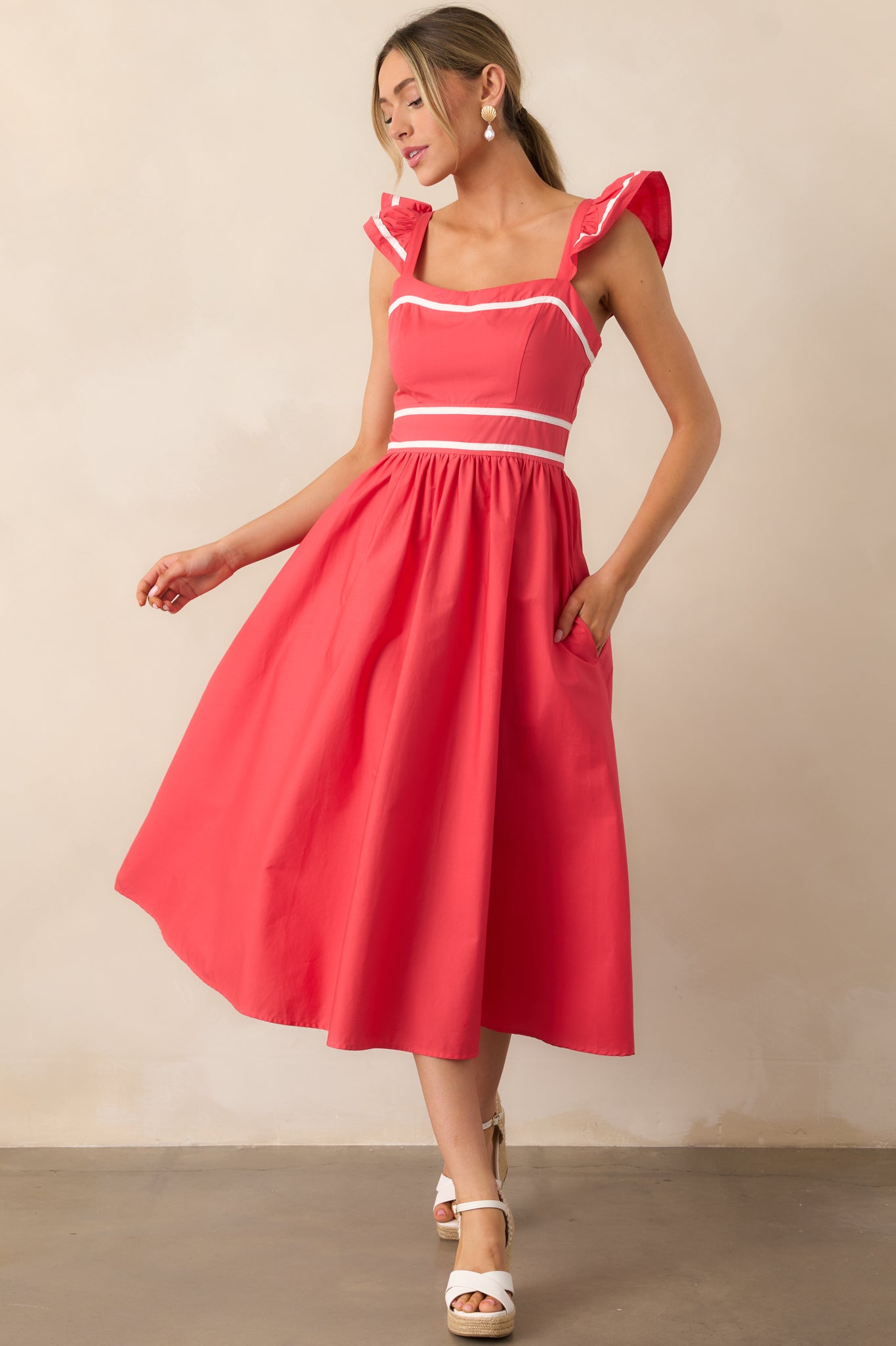 A stylish red dress showcasing functional pockets, a structured fit, and elegant flutter sleeve details.