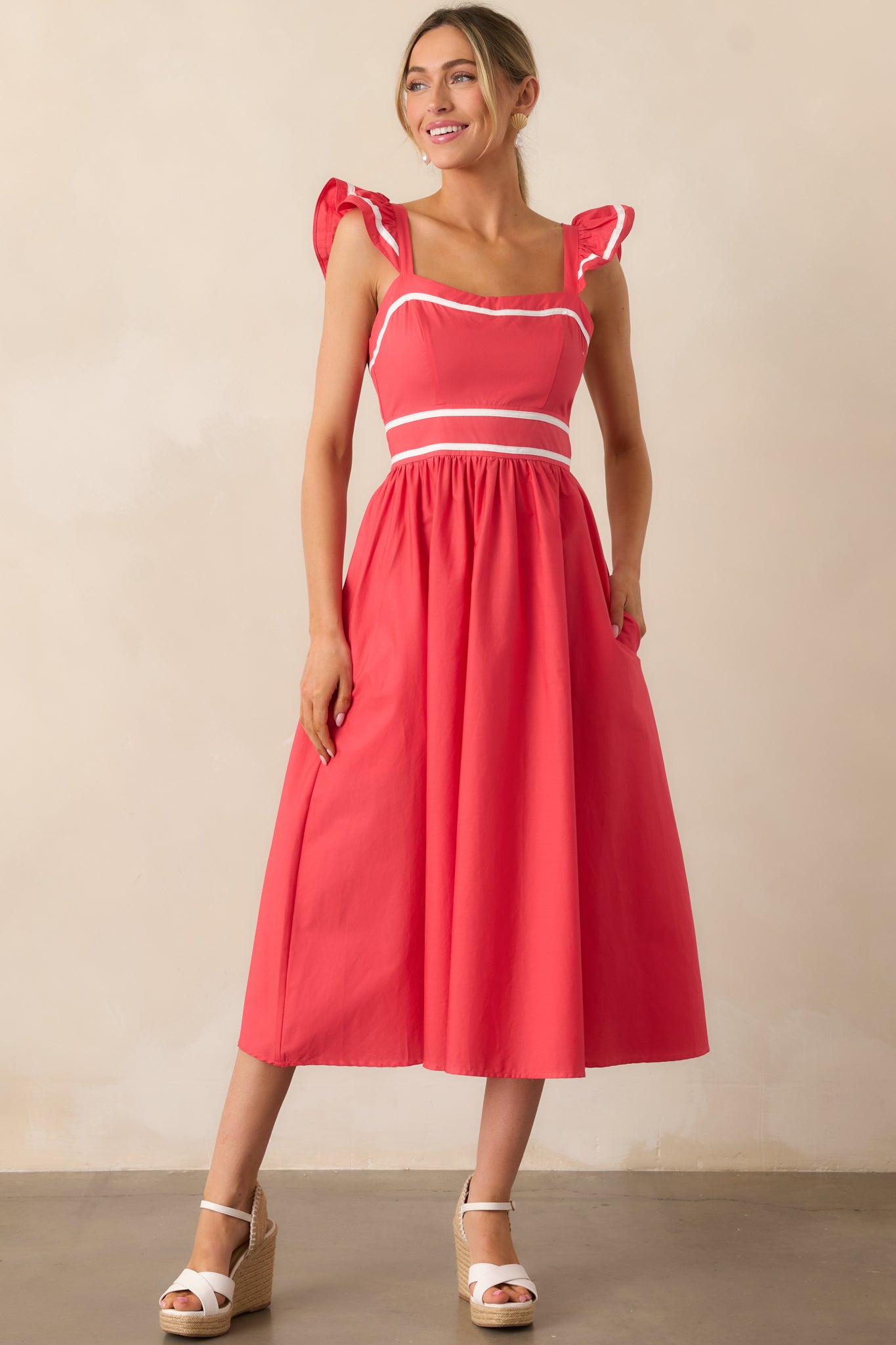 A vibrant tomato red dress with delicate flutter sleeves, a knee-length cut, and crisp white hem accents.