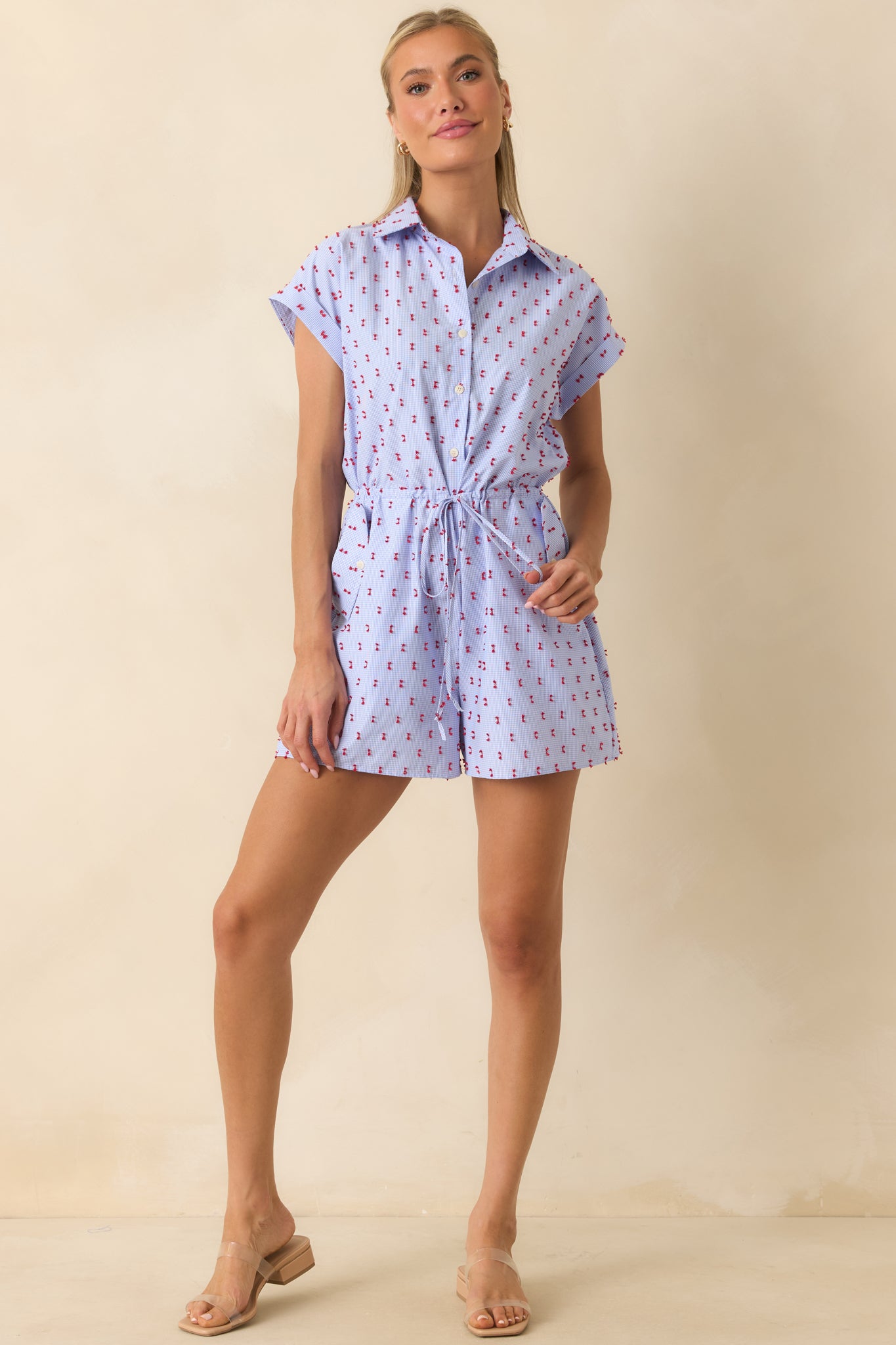 Detailed view of the button-front bodice, red tufted embroidery, and collared neckline on the gingham romper.