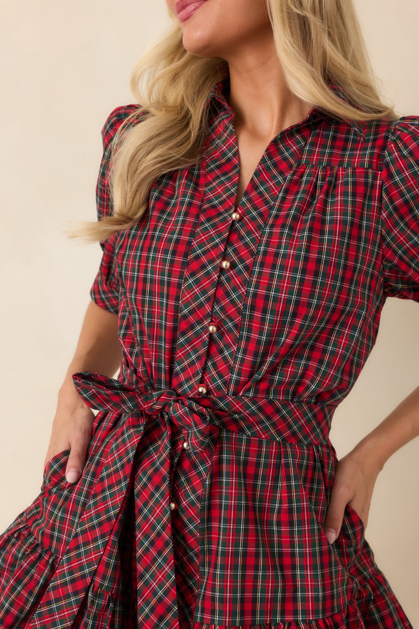 Close-up of the red and green plaid cotton dress highlighting the gold-tone buttons, collar, puff sleeves, and fabric texture.