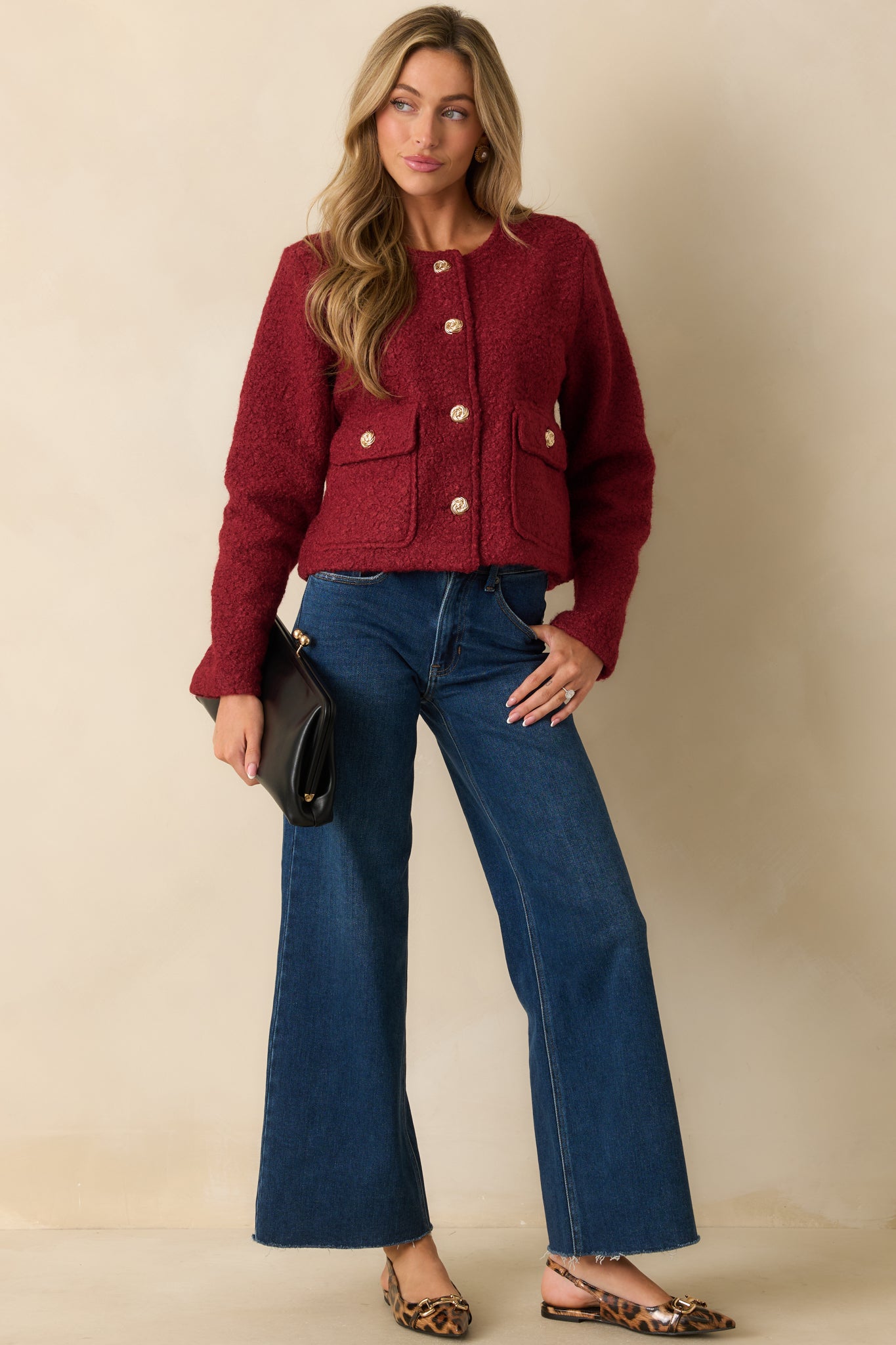 Cherry red bouclé jacket with a round neckline, long sleeves, front flap pockets, and gold button closures.