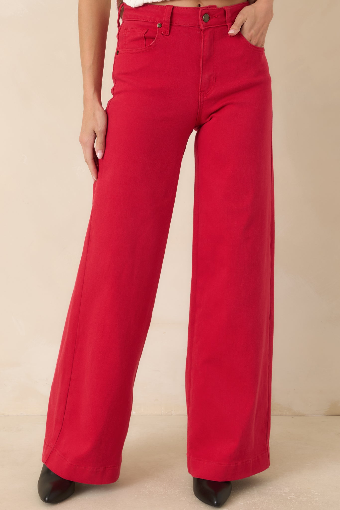 Detailed view of the vibrant red jeans featuring classic five-pocket styling, button-and-zip closure, and structured waistband.