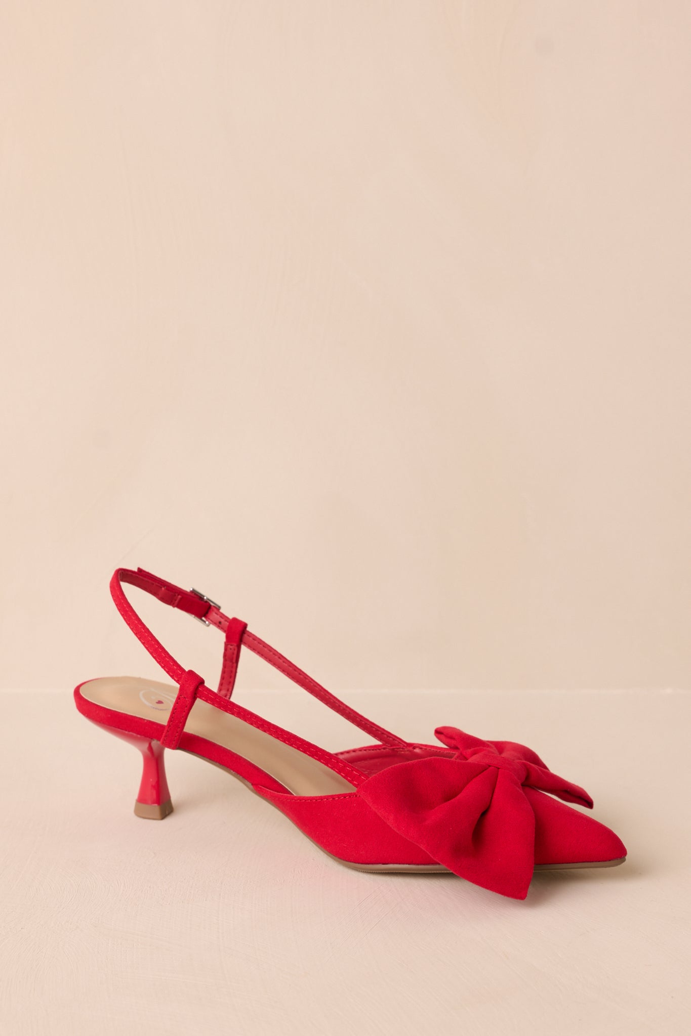 Alternate side view of the red kitten heels showing the sleek design of the pointed toe, the bow detail, and the slightly curved heel.