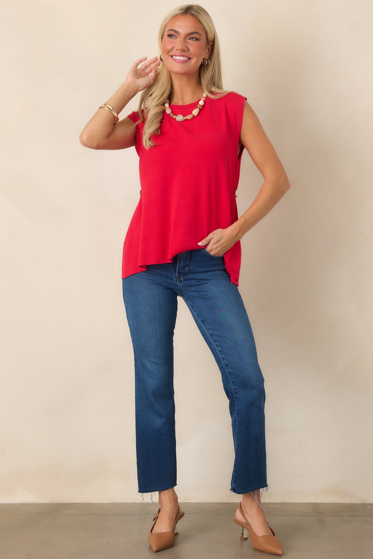 Lightweight red knit top showcasing a relaxed draped shape, rounded neckline, cap sleeves, and decorative gold-tone hardware at the sides.