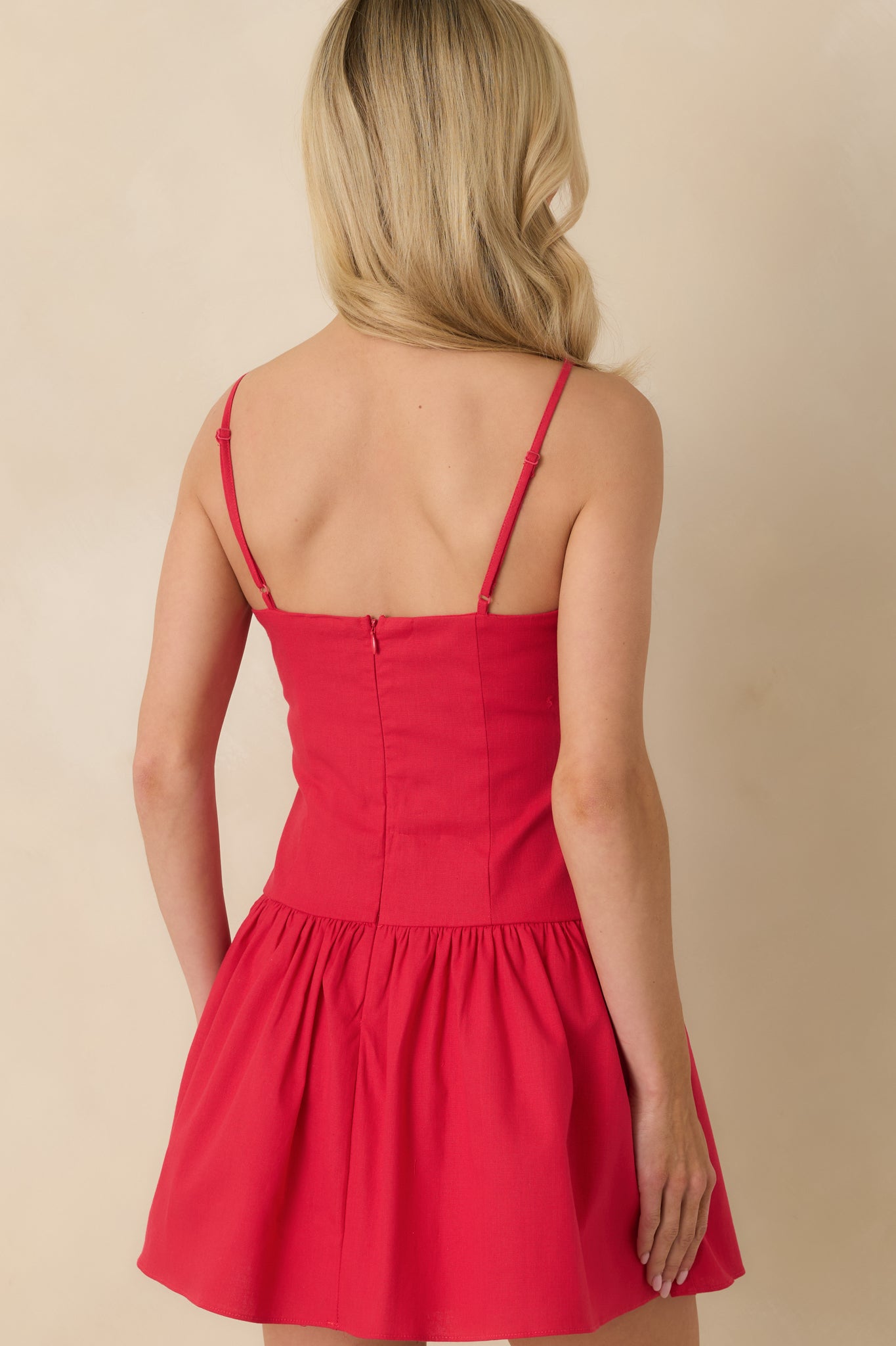 Back view of the red mini dress showing the clean silhouette, adjustable straps, and concealed zipper closure for a secure fit.