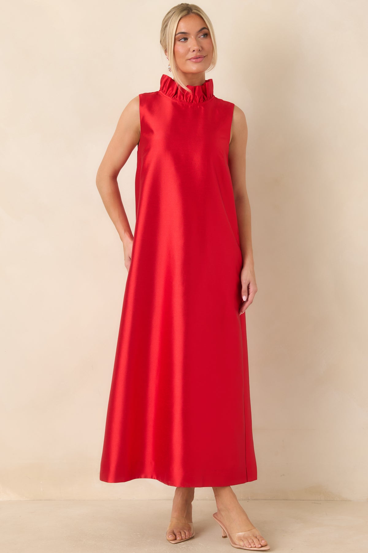 Bright red dress showcasing a minimalist sleeveless shape, ruffled collar, and softly flowing maxi skirt.