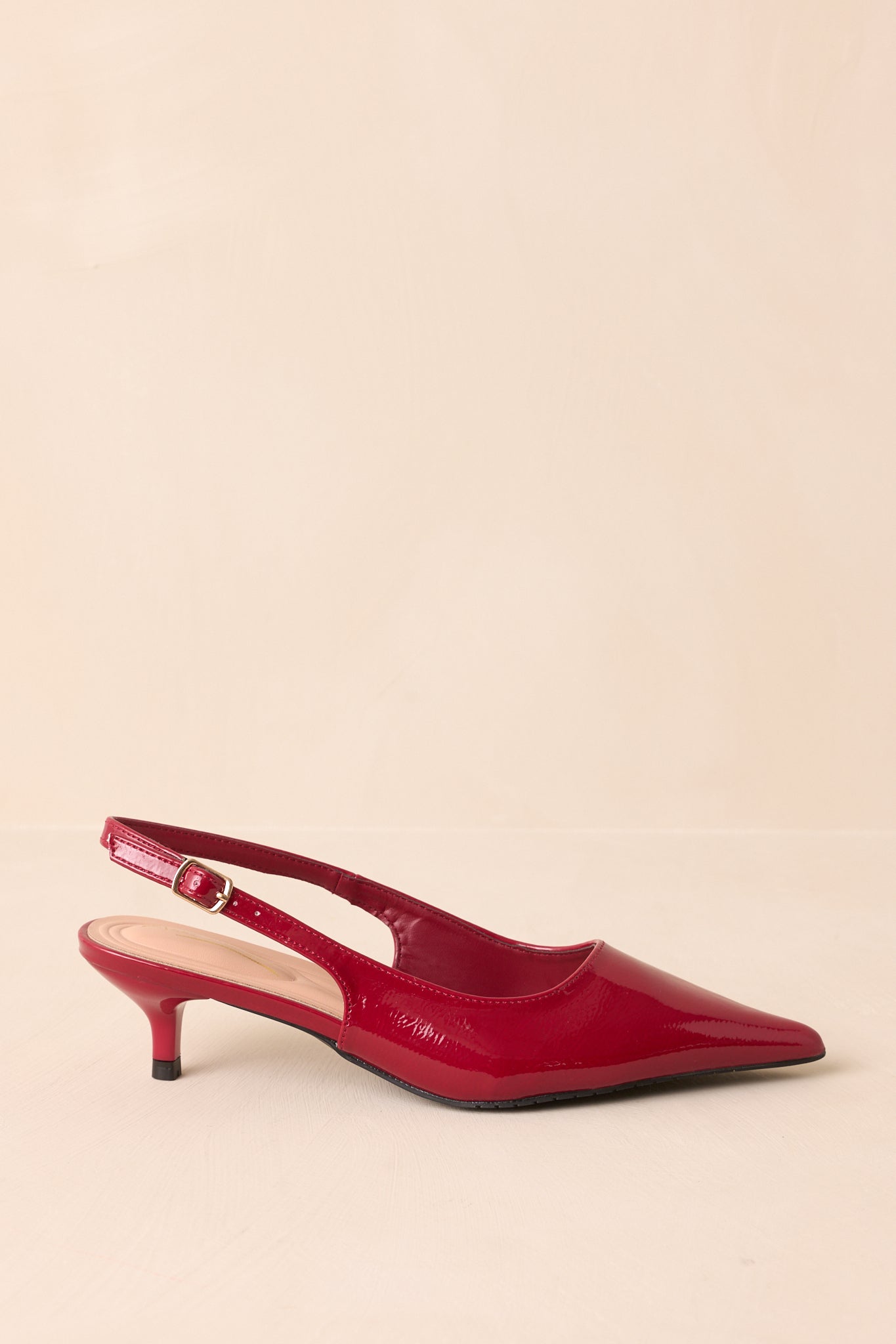 Red patent slingback heels shown from the side, highlighting the pointed toe and slim kitten heel.