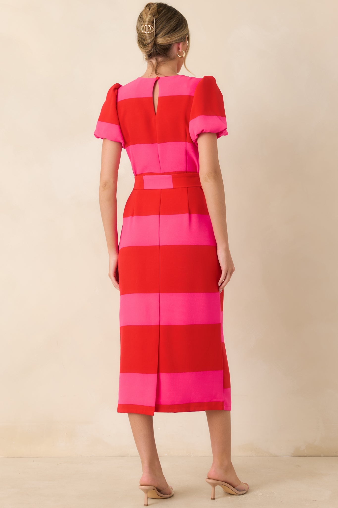 Back view of the red and pink striped midi dress featuring a keyhole button closure and back slit.