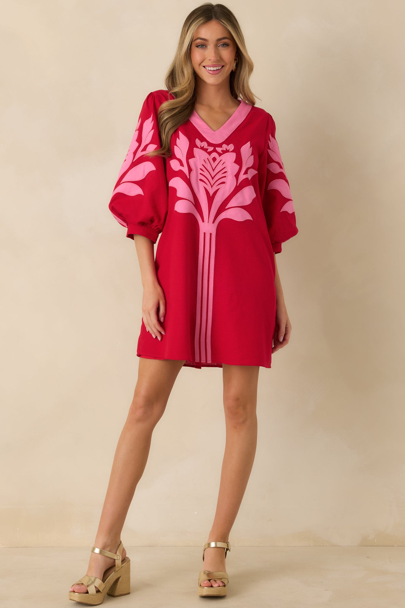 Relaxed-fit red and pink mini dress with contrast trim along the V-neckline, puffed sleeves, gathered cuffs, and a straight-cut hemline.