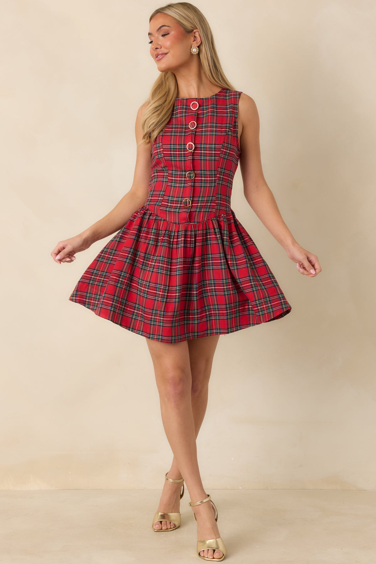 Classic red plaid mini dress featuring a round neckline, curved drop waist, and decorative gold-rimmed buttons.