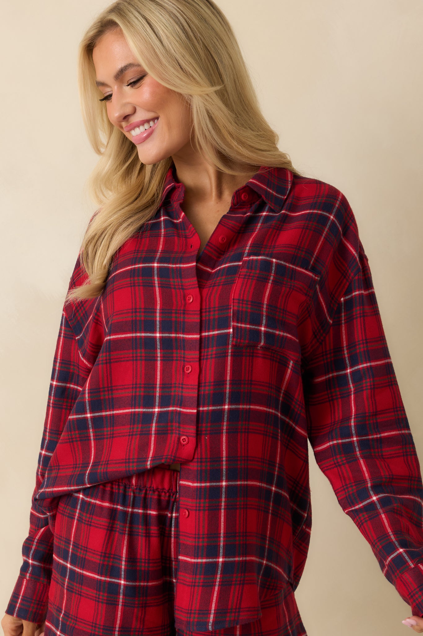 Red plaid top cropped mid-torso, highlighting the relaxed fit and long sleeves in flannel fabric.