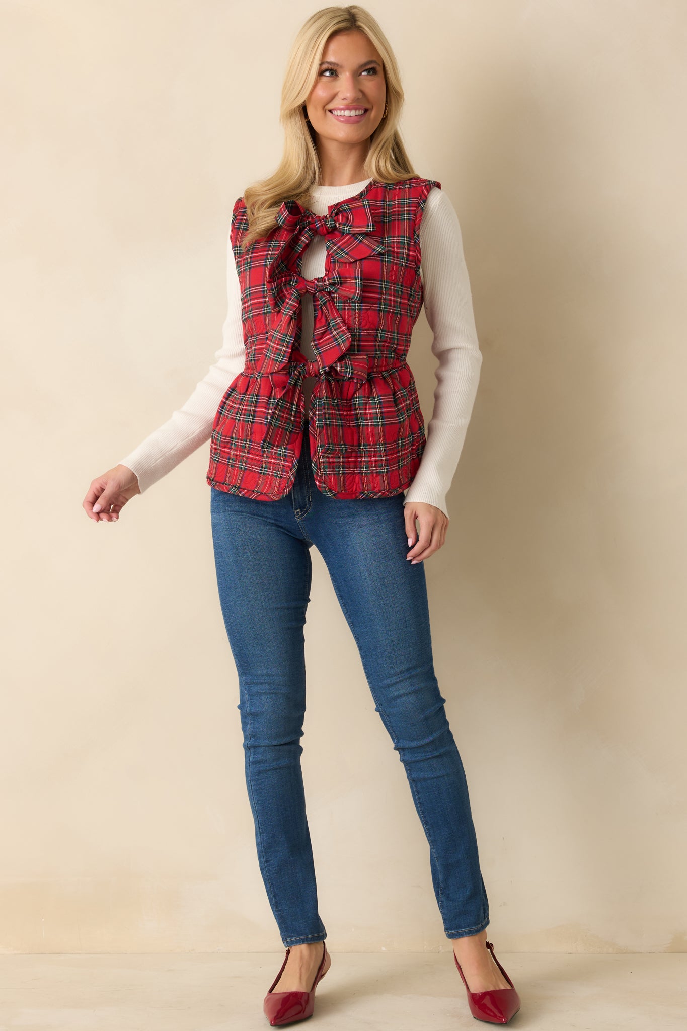 Tailored red plaid vest with sleeveless cut, decorative bow closures, and quilted texture throughout.