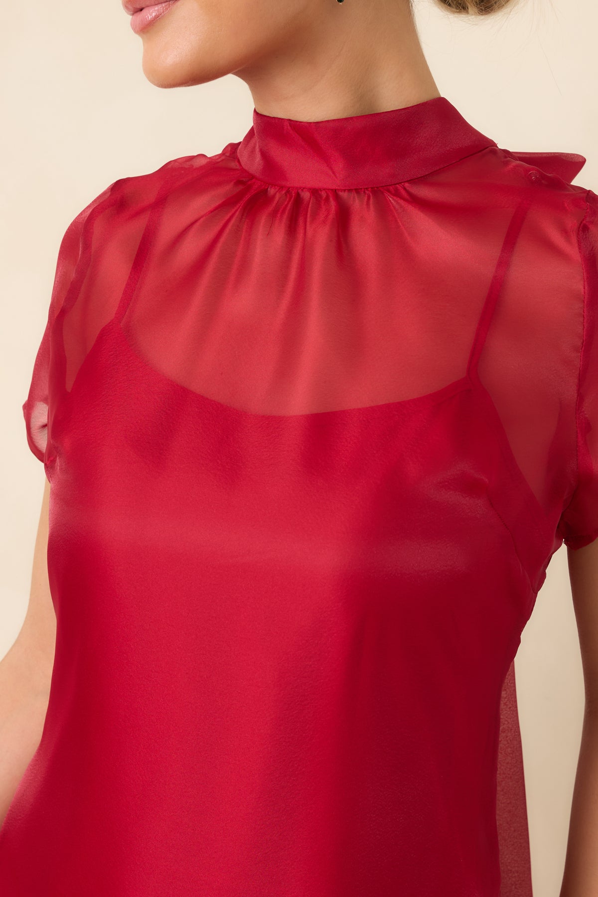 Close-up of the red dress showing the sheer mock neckline, lightweight overlay, and delicate fabric detailing.
