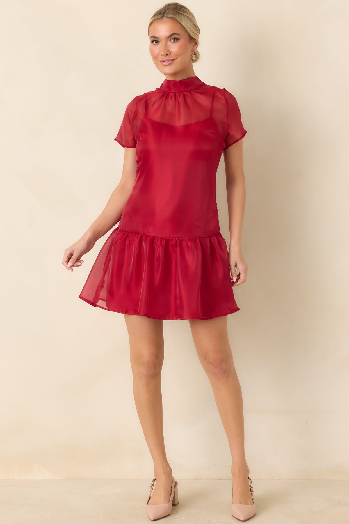 Red mini dress with a sheer mock neckline, translucent short sleeves, and a gathered ruffle hem.