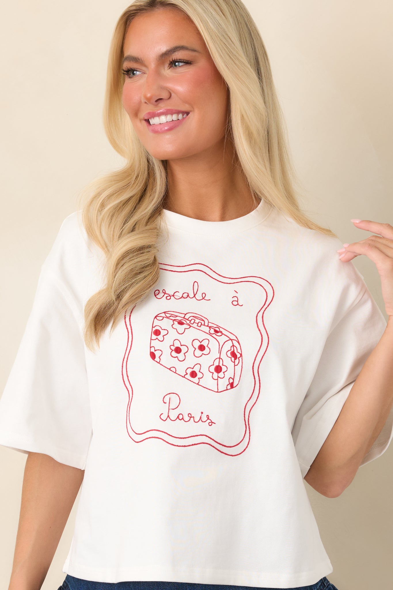 Front view emphasizing the detailed red suitcase embroidery and decorative floral elements across the soft top.