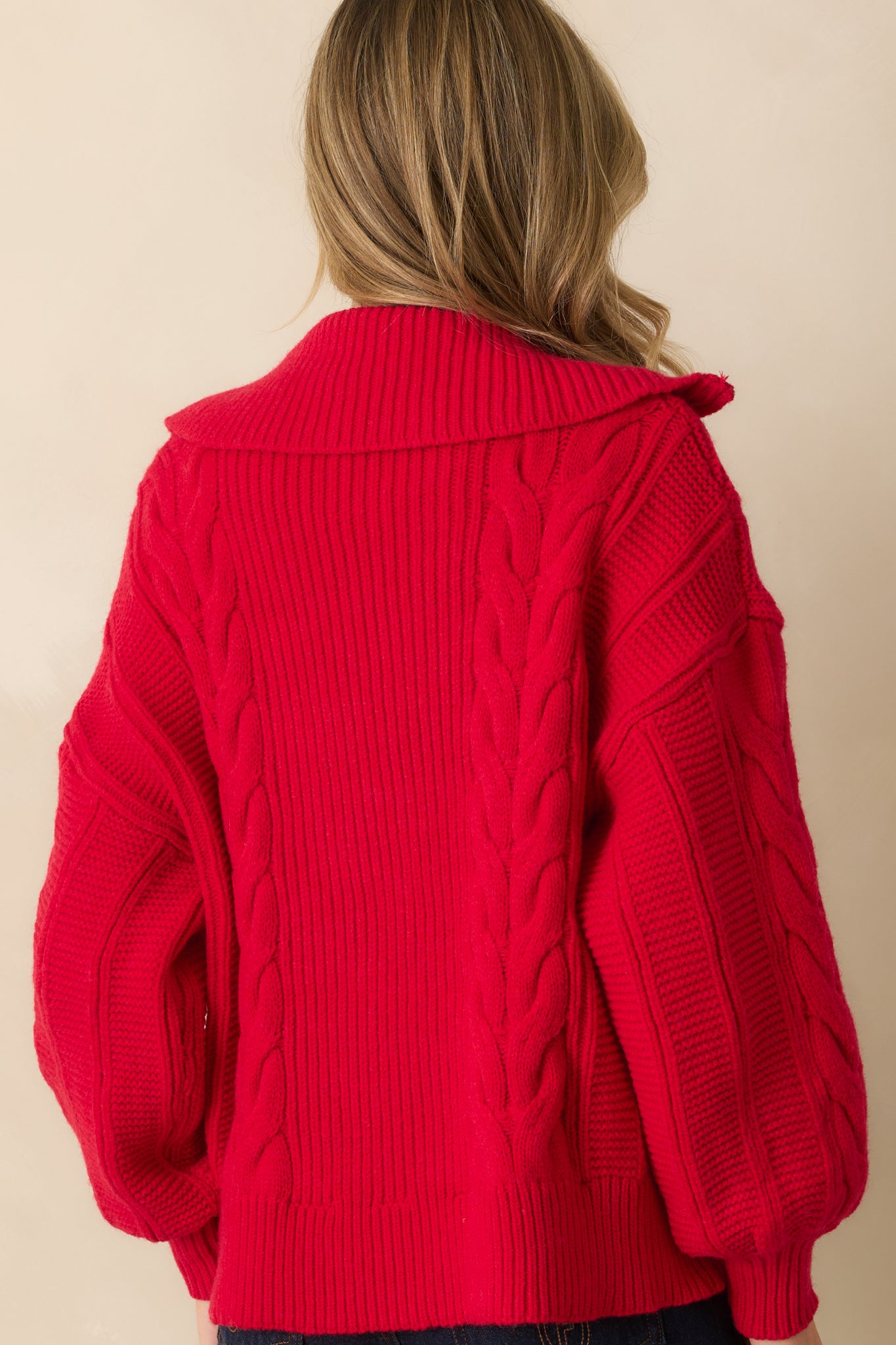 Rear view of the red sweater showing the relaxed fit, long sleeves, and ribbed hem.