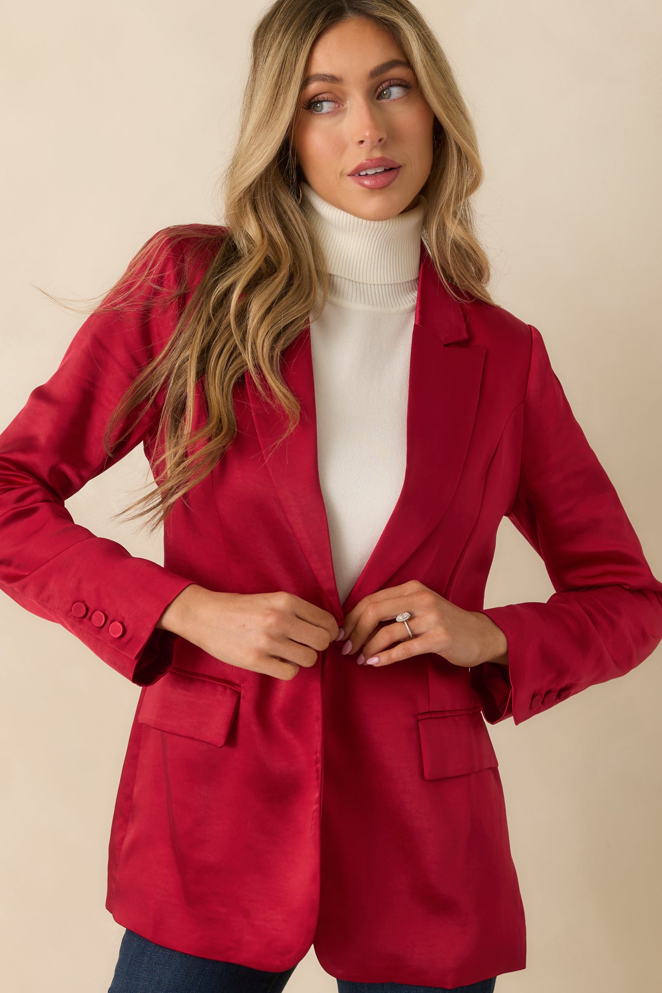 Detail of the buttoned cuffs and long sleeves on the red tailored blazer.