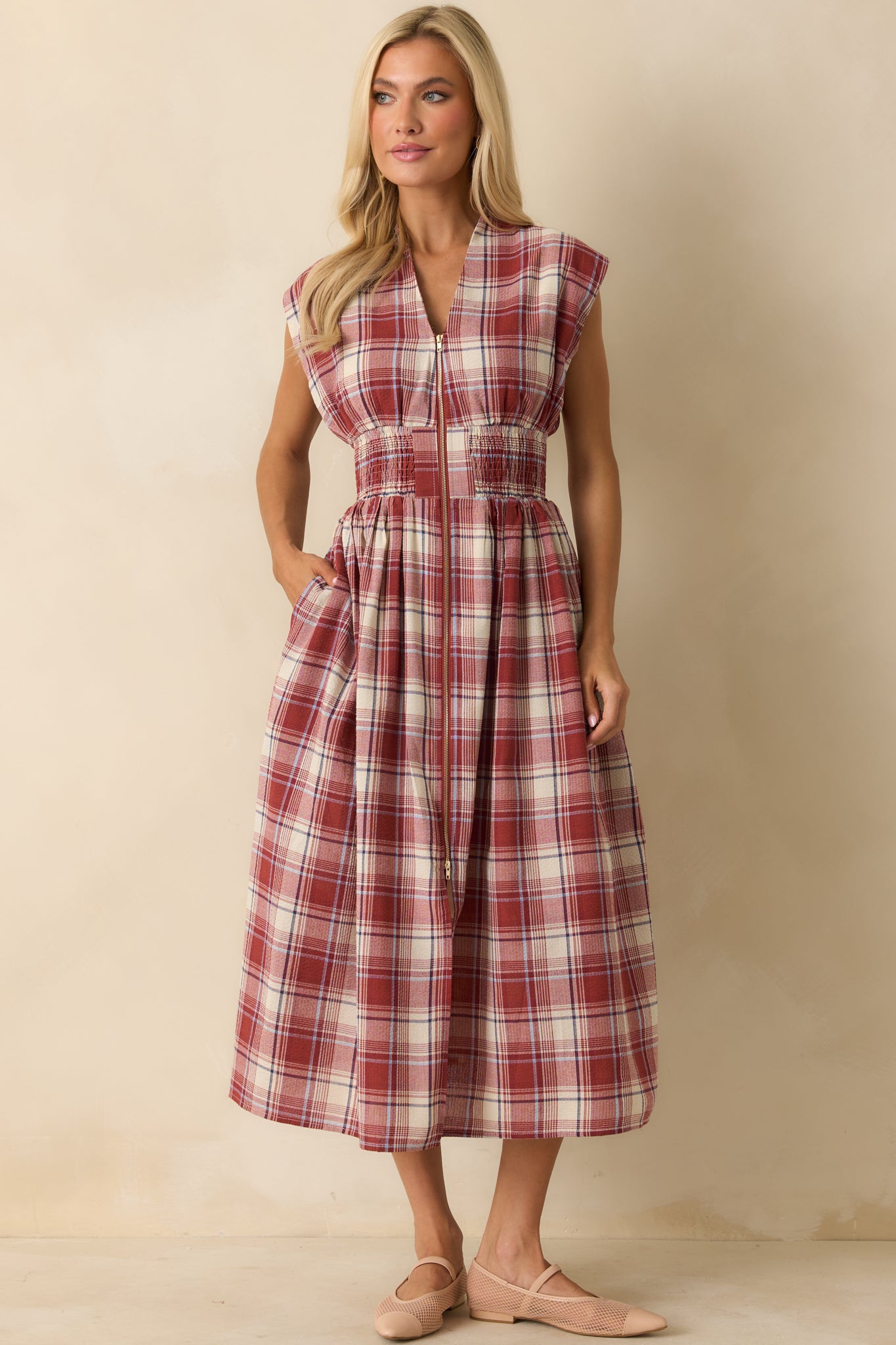 Front view of red tartan midi dress highlighting smocked waist, hip pockets, and elegant V-neckline.