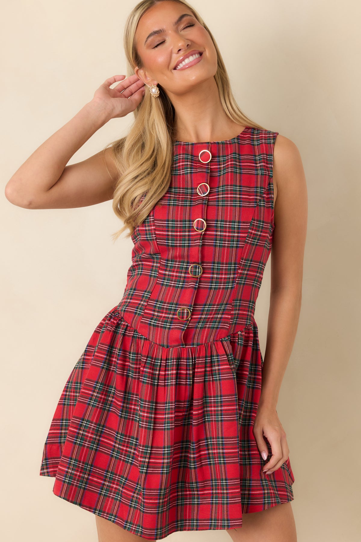 Red tartan mini dress showcasing the sleeveless fitted bodice, round neckline, and decorative button-front design.