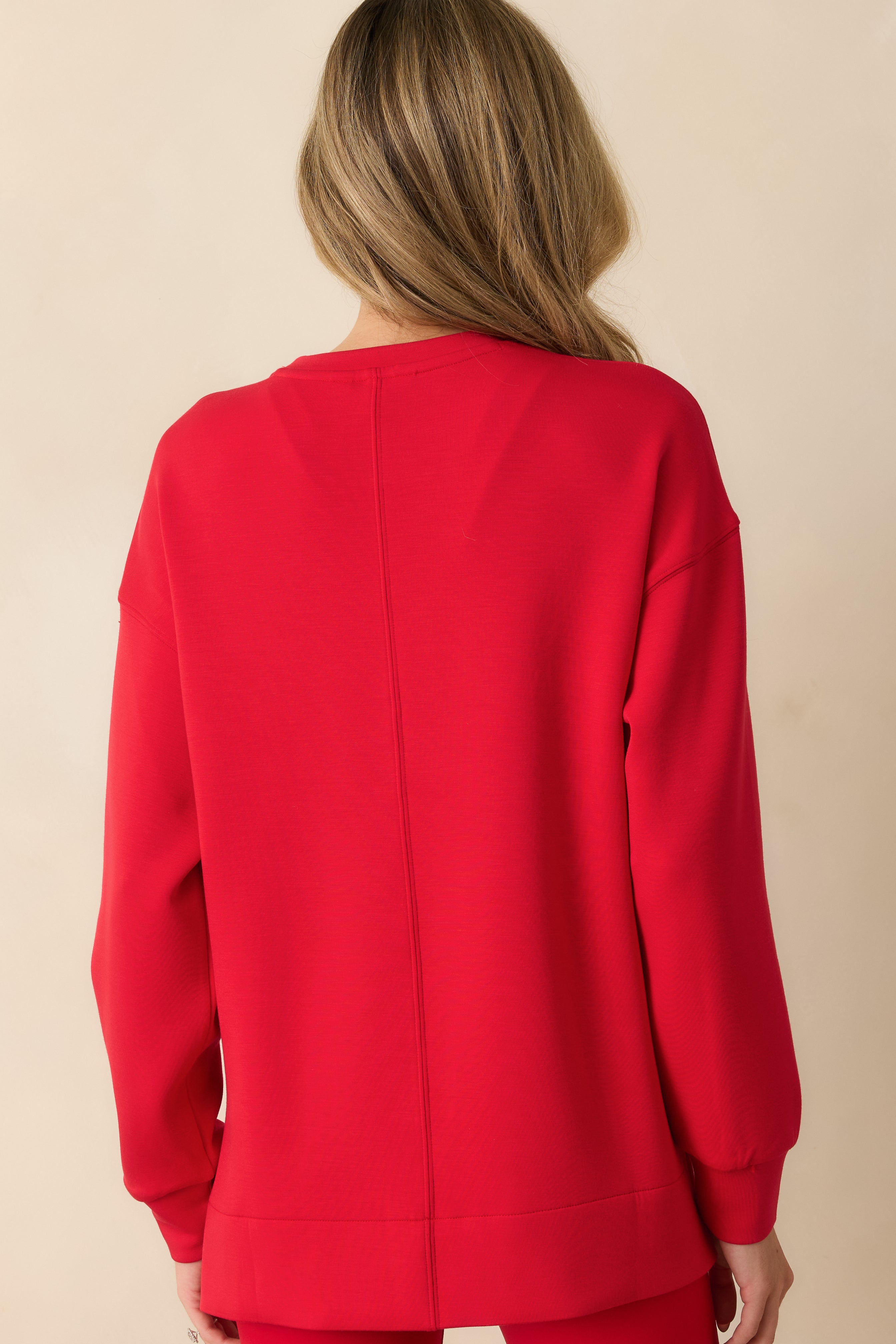 Rear view of the red tunic highlighting its relaxed fit and fluid drape from shoulders to hem.