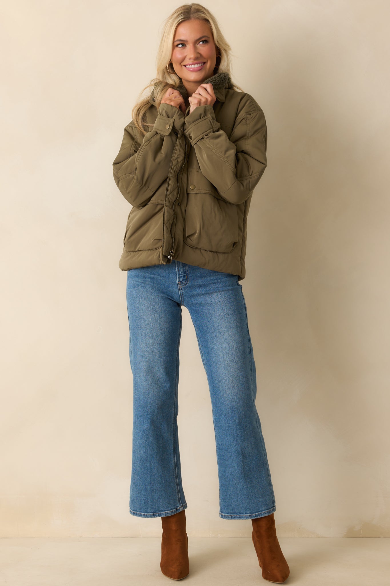 Relaxed army green puffer jacket with long sleeves, snap button cuffs, a sherpa-lined collar, and functional front patch pockets.