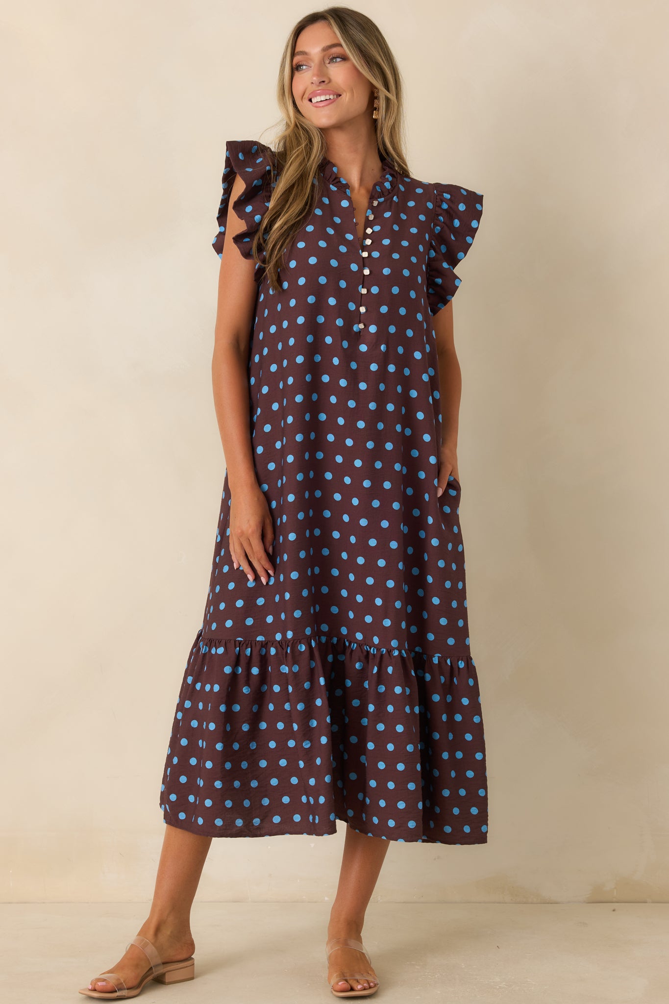 Relaxed fit brown midi dress featuring playful blue dots, flutter sleeves, and feminine layered hem details.