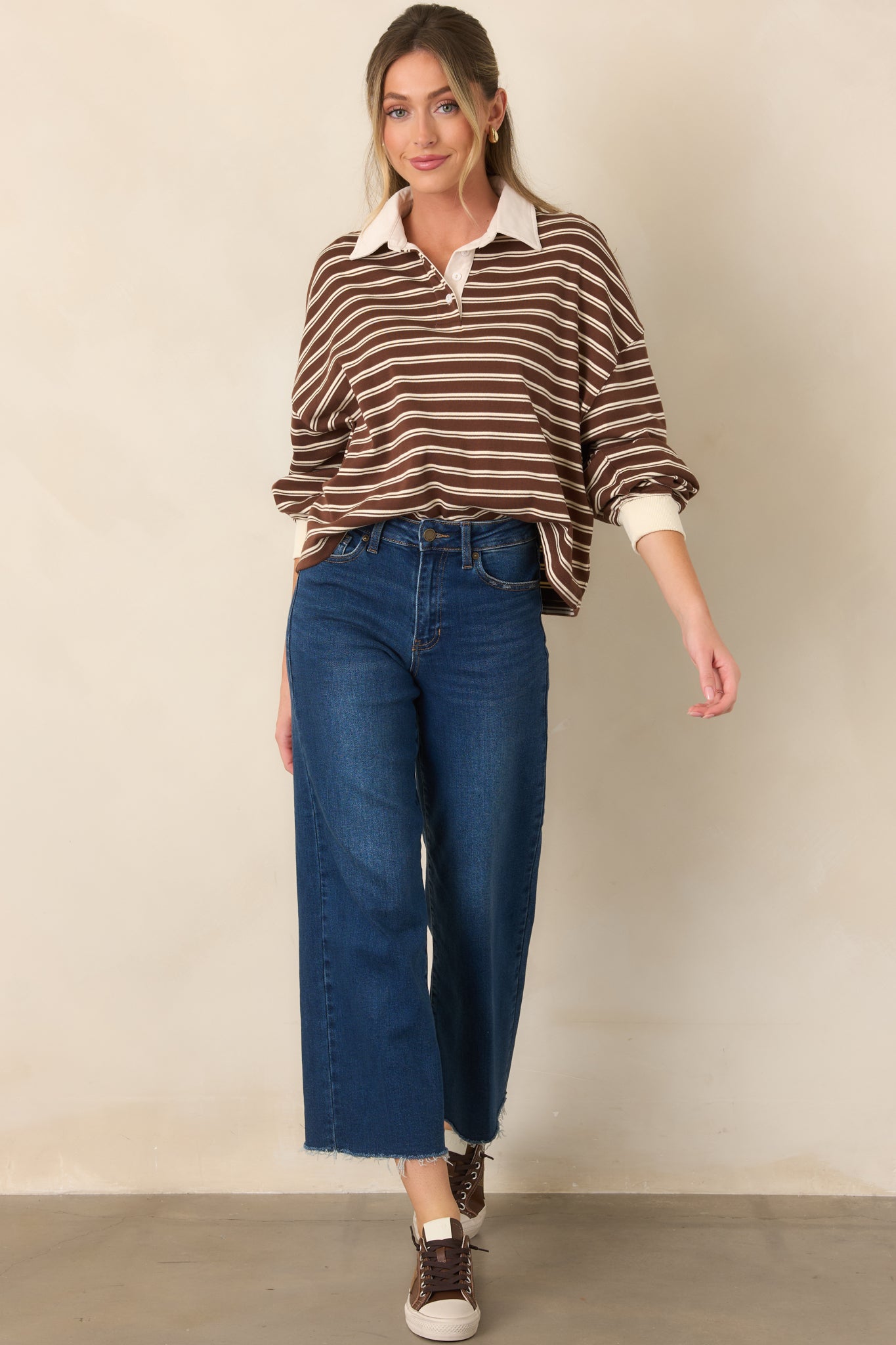 Relaxed brown sweater designed with horizontal ivory stripes, a button placket, wide collar, and boxy silhouette.
