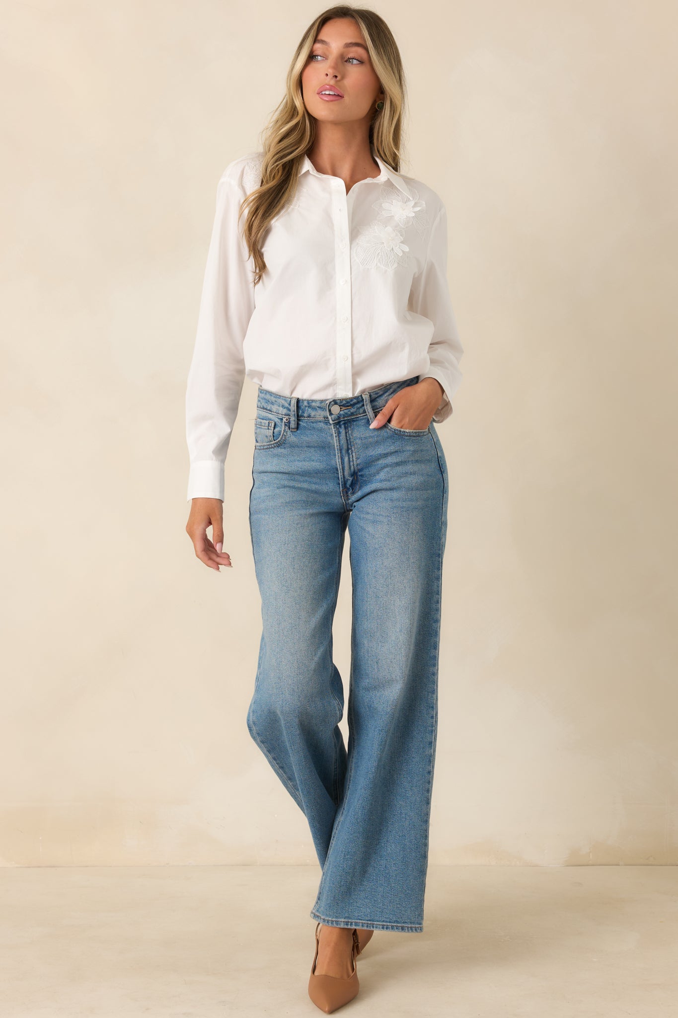 Relaxed fit button-up top showcasing a collared neckline, woven texture, and decorative floral appliqué along the front.