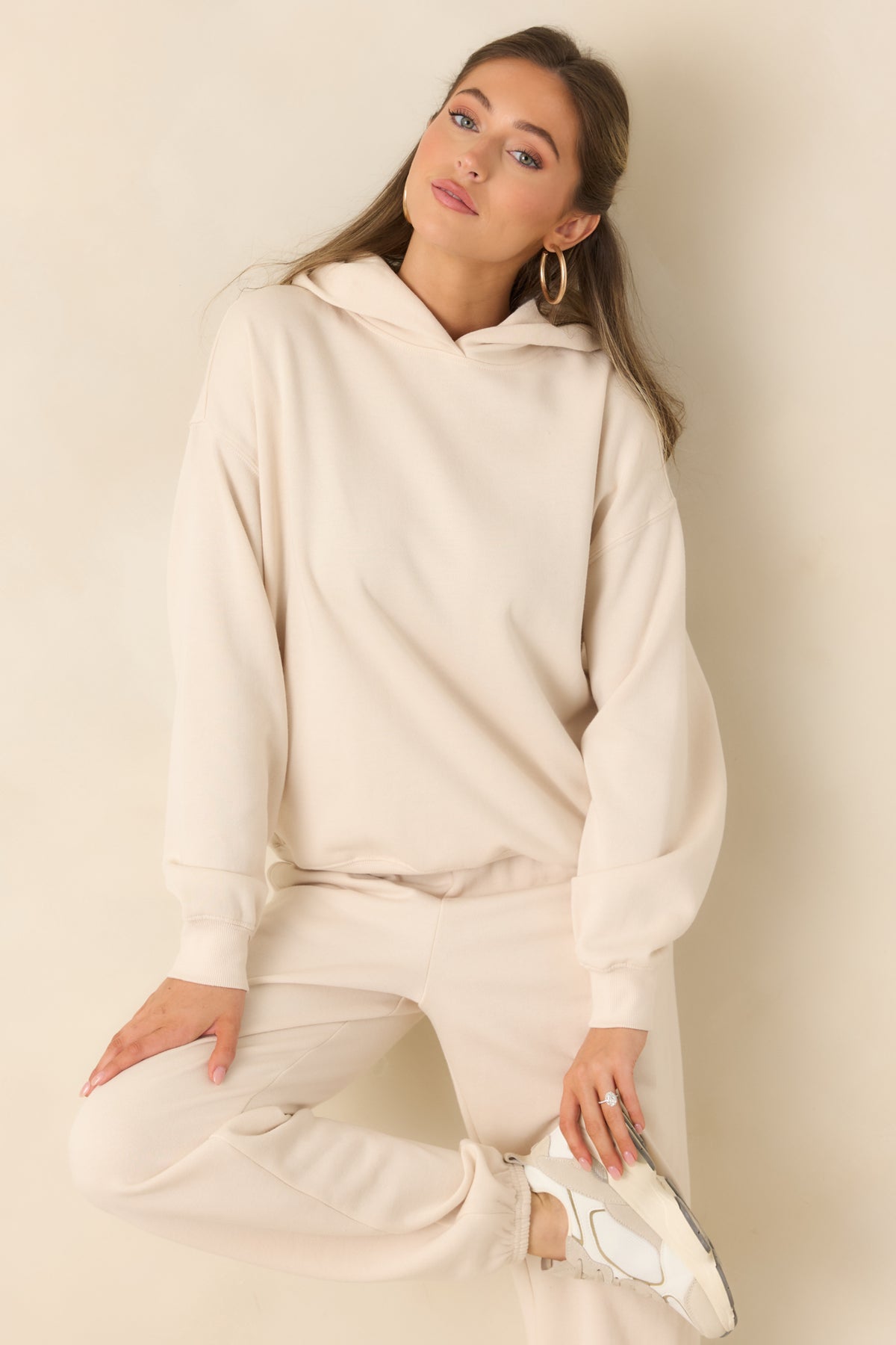Relaxed cream hoodie with long sleeves and a structured ribbed hem.