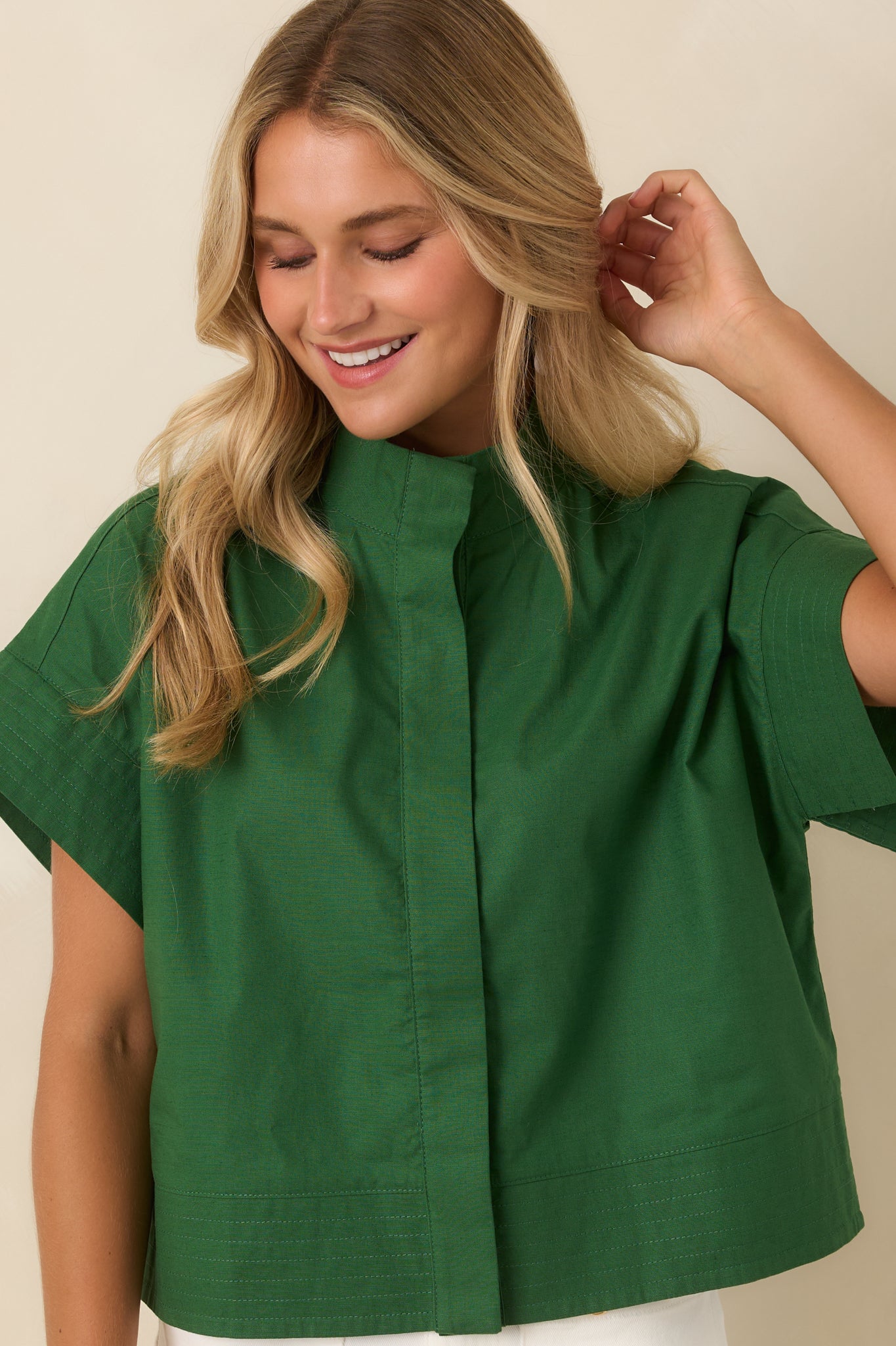 Relaxed cropped top highlighting the button-front design, cuffed sleeves, and understated tailored appearance.