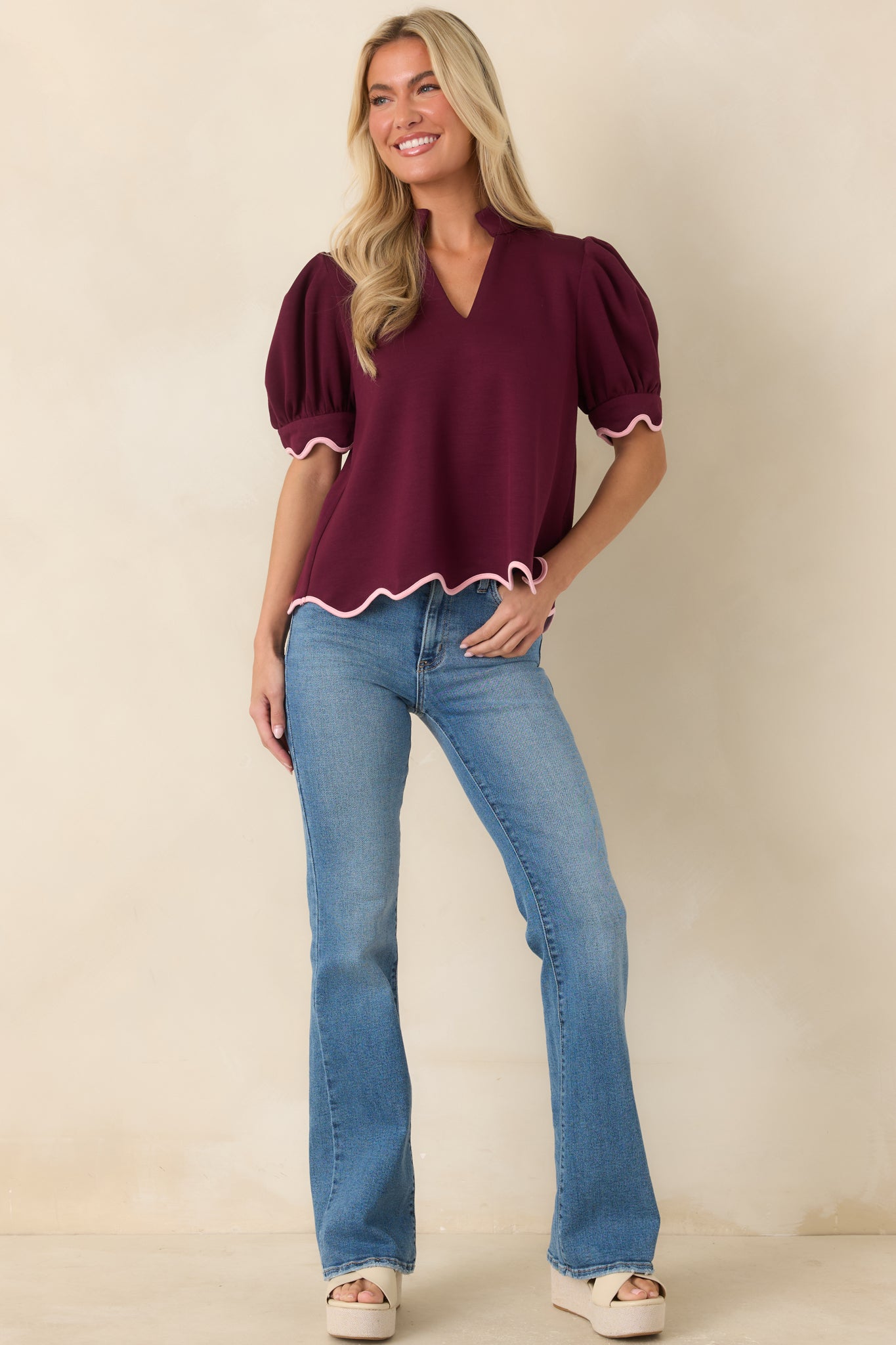 Relaxed-fit burgundy top designed with subtle volume at the sleeves and blush pink trim accenting the hemline.