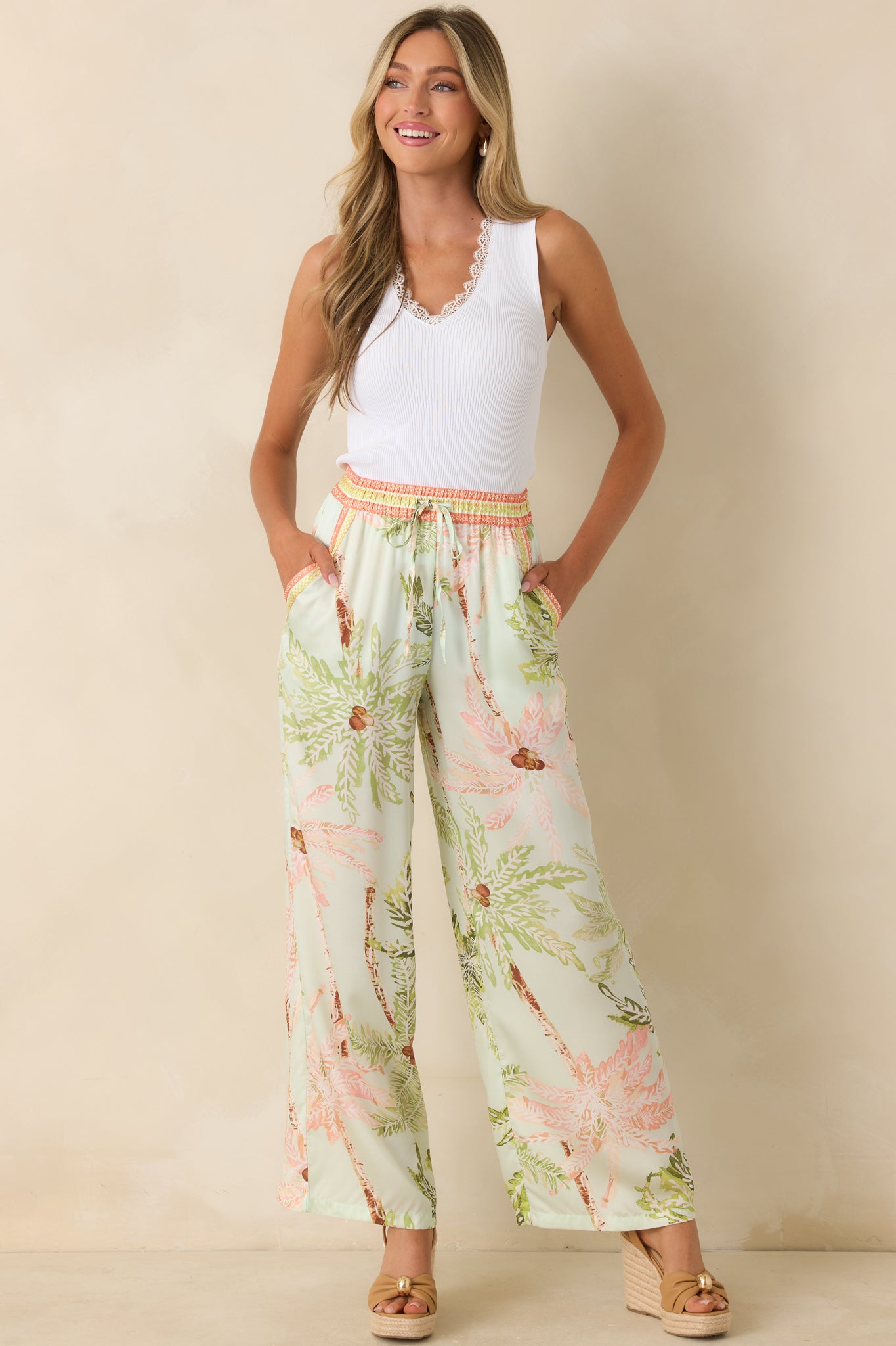 Relaxed-fit mint pants featuring contrast-trim side pockets and an allover palm print in green, blush, and warm brown.